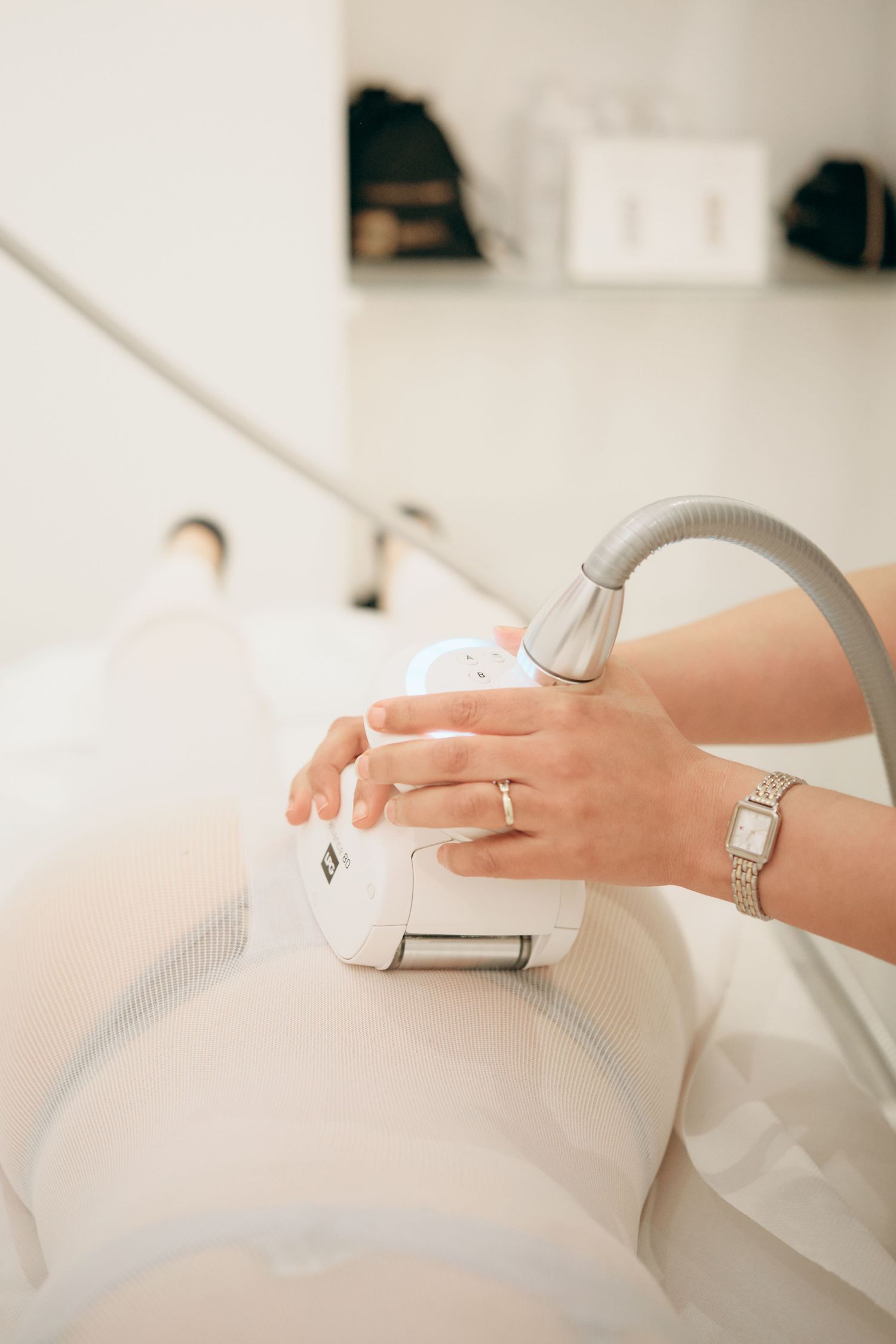 Aesthetician performing laser hair removal treatment on a patient's leg in a modern beauty clinic.