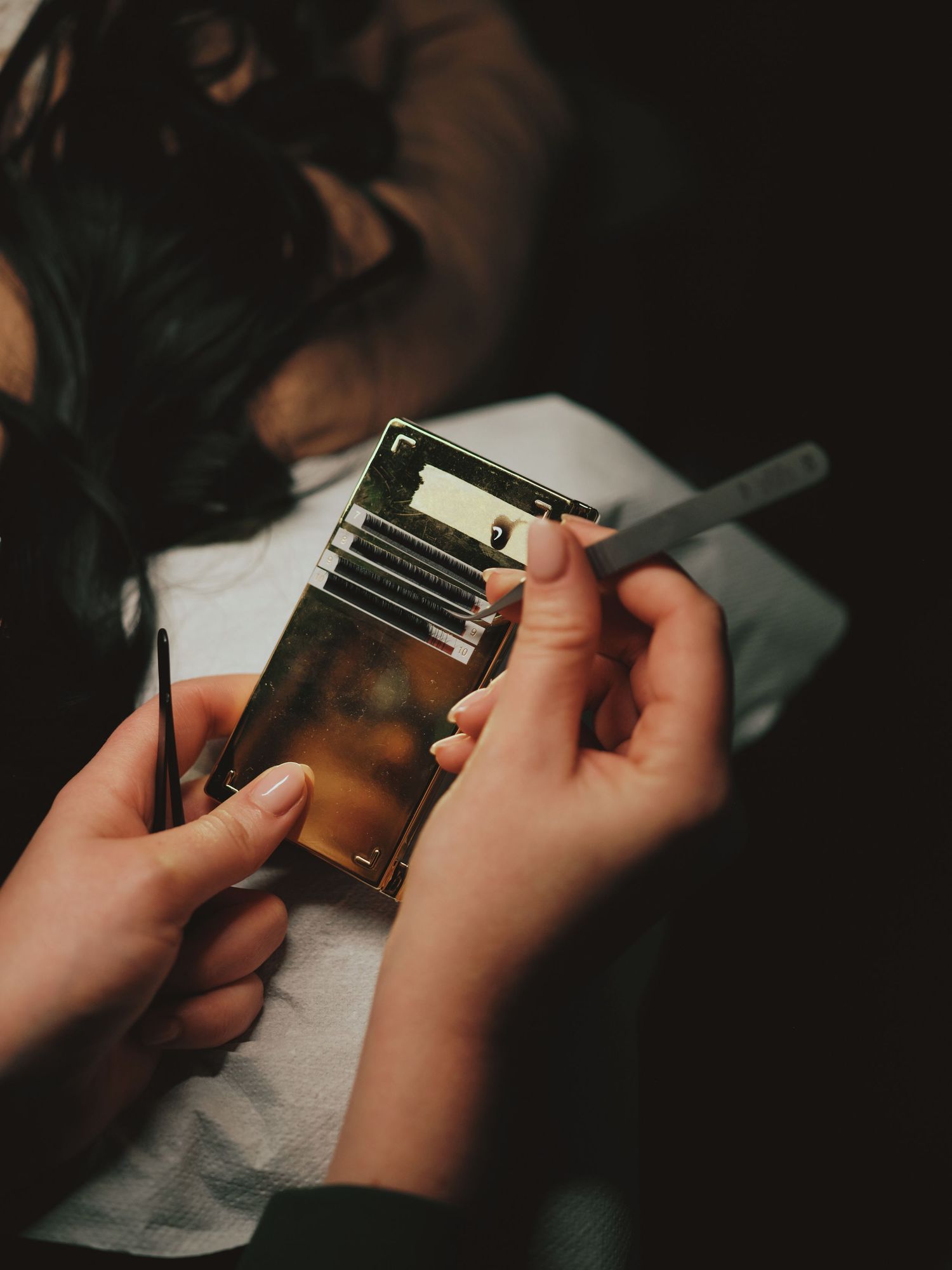 Hands holding a gold metal card wallet while inserting a card, with a cigarette visible in dim lighting.