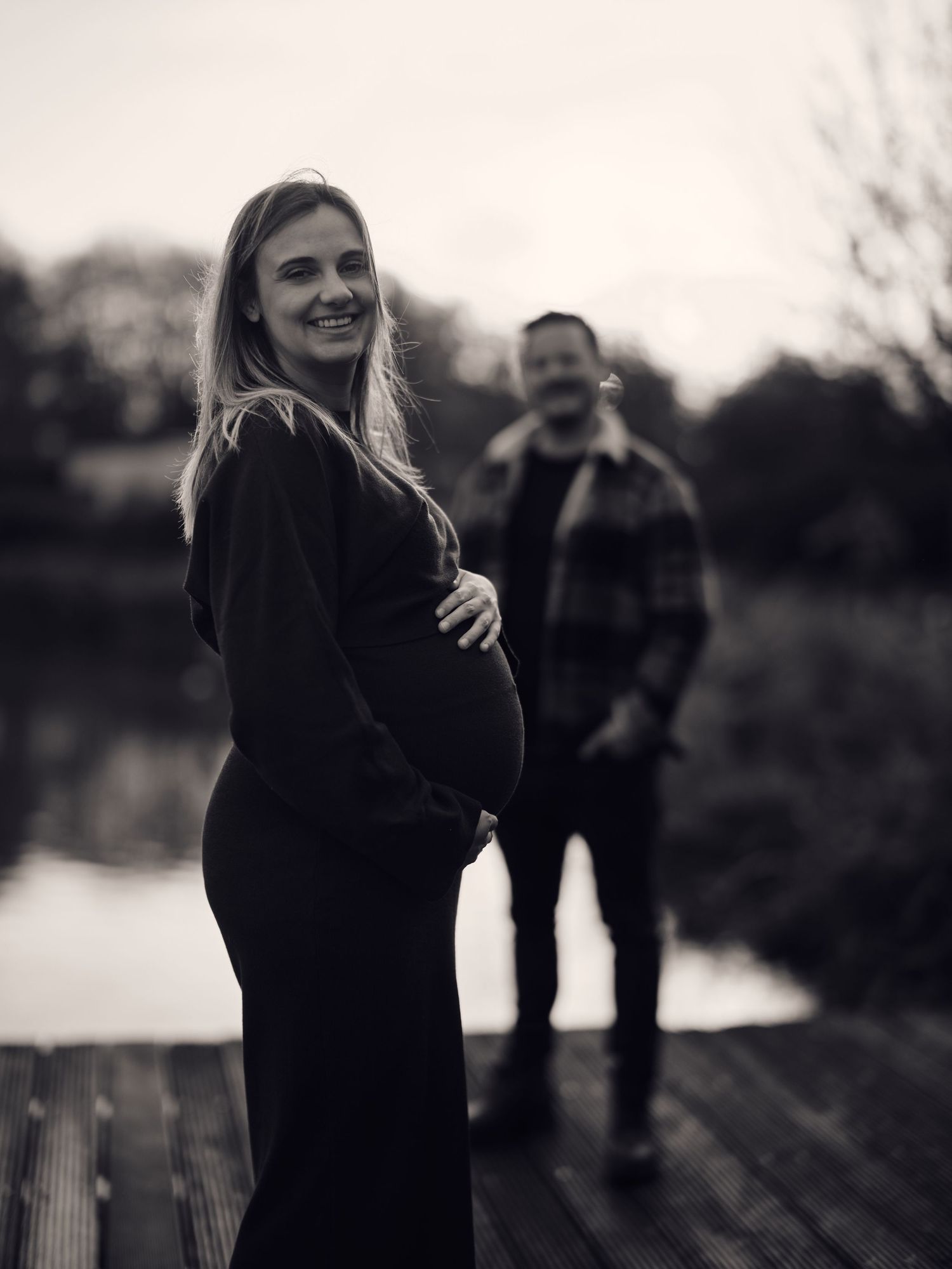 A romantic black and white series of photos showing a couple embracing on a wooden dock by a lake.