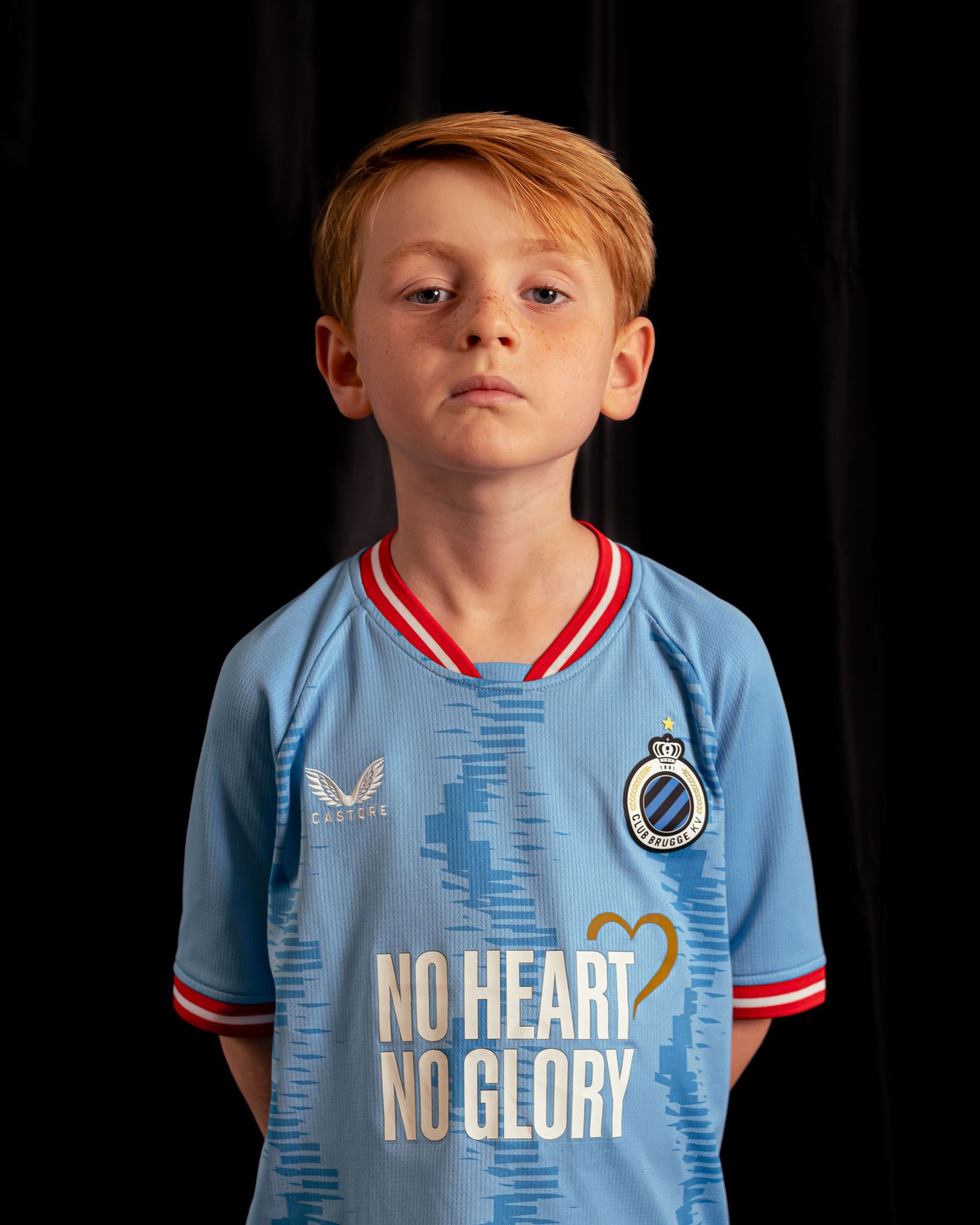 Young person wearing light blue sports jersey with 'No Heart No Glory' text against black background.