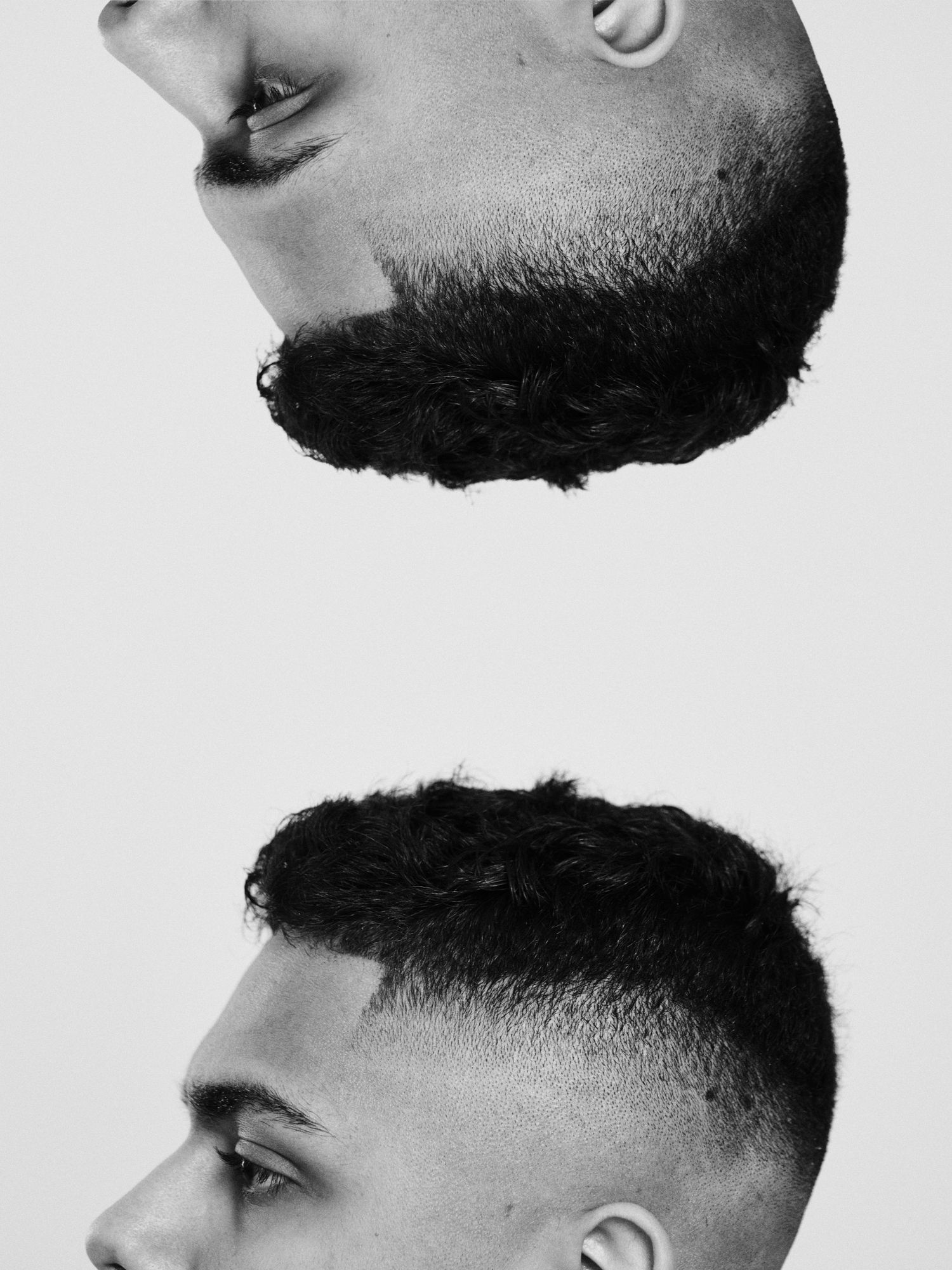 Black and white photo showing two angles of a man with curly hair and a fade haircut, one image flipped upside down.