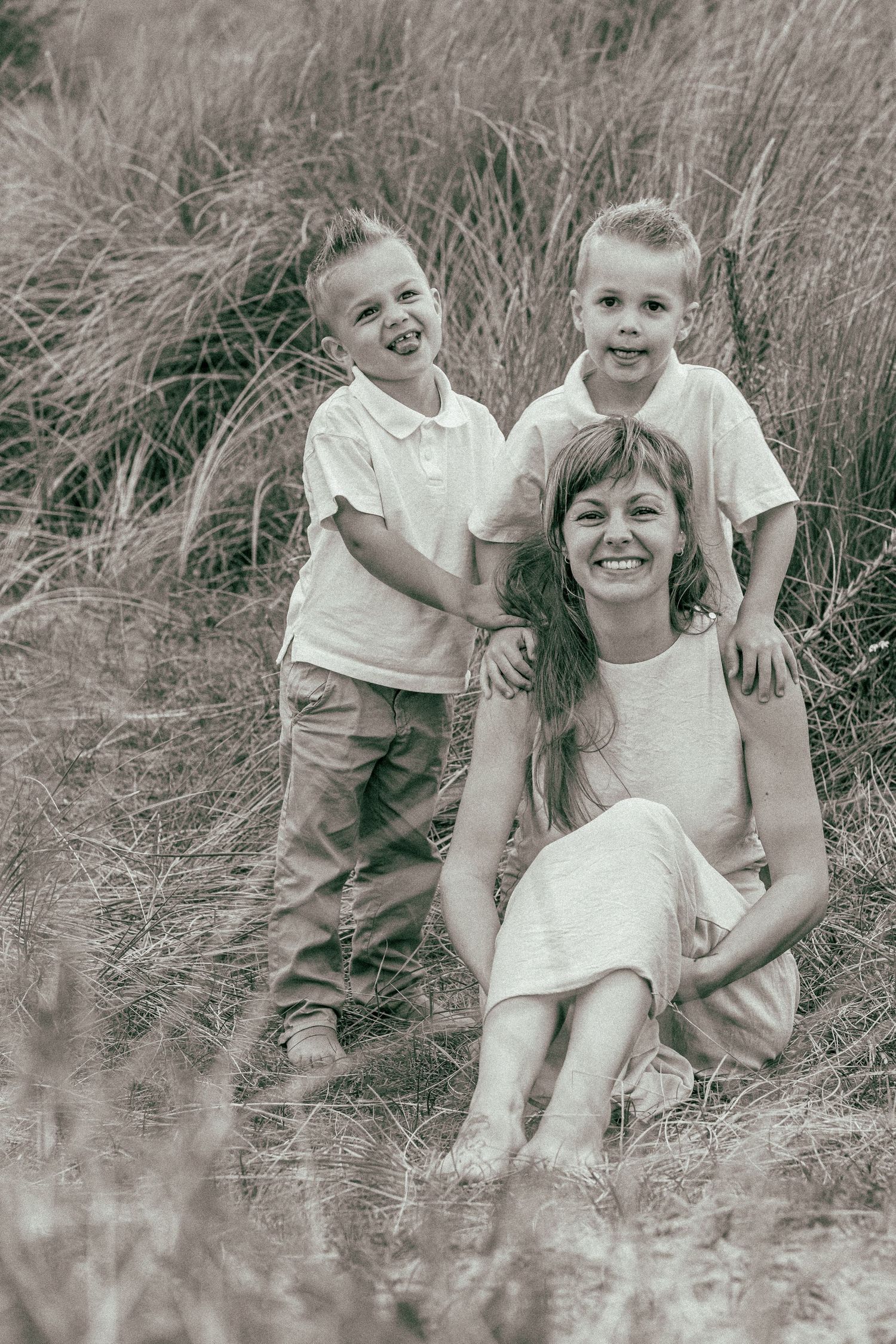 Family photo session in tall grass field with natural lighting.