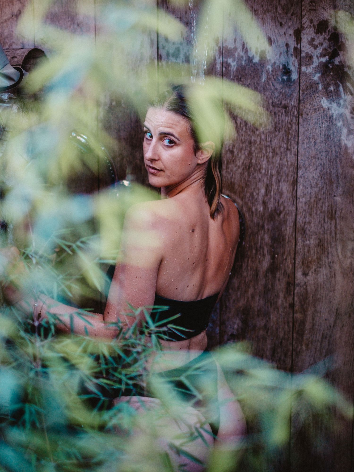 Dreamy portrait through leaves against wooden wall background.