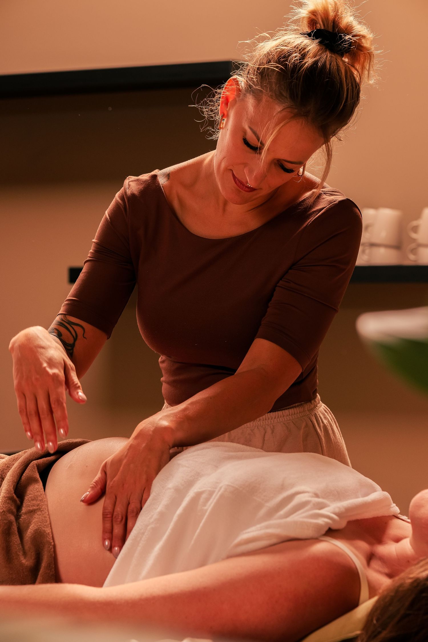 A massage therapist in brown attire performing a professional massage treatment.