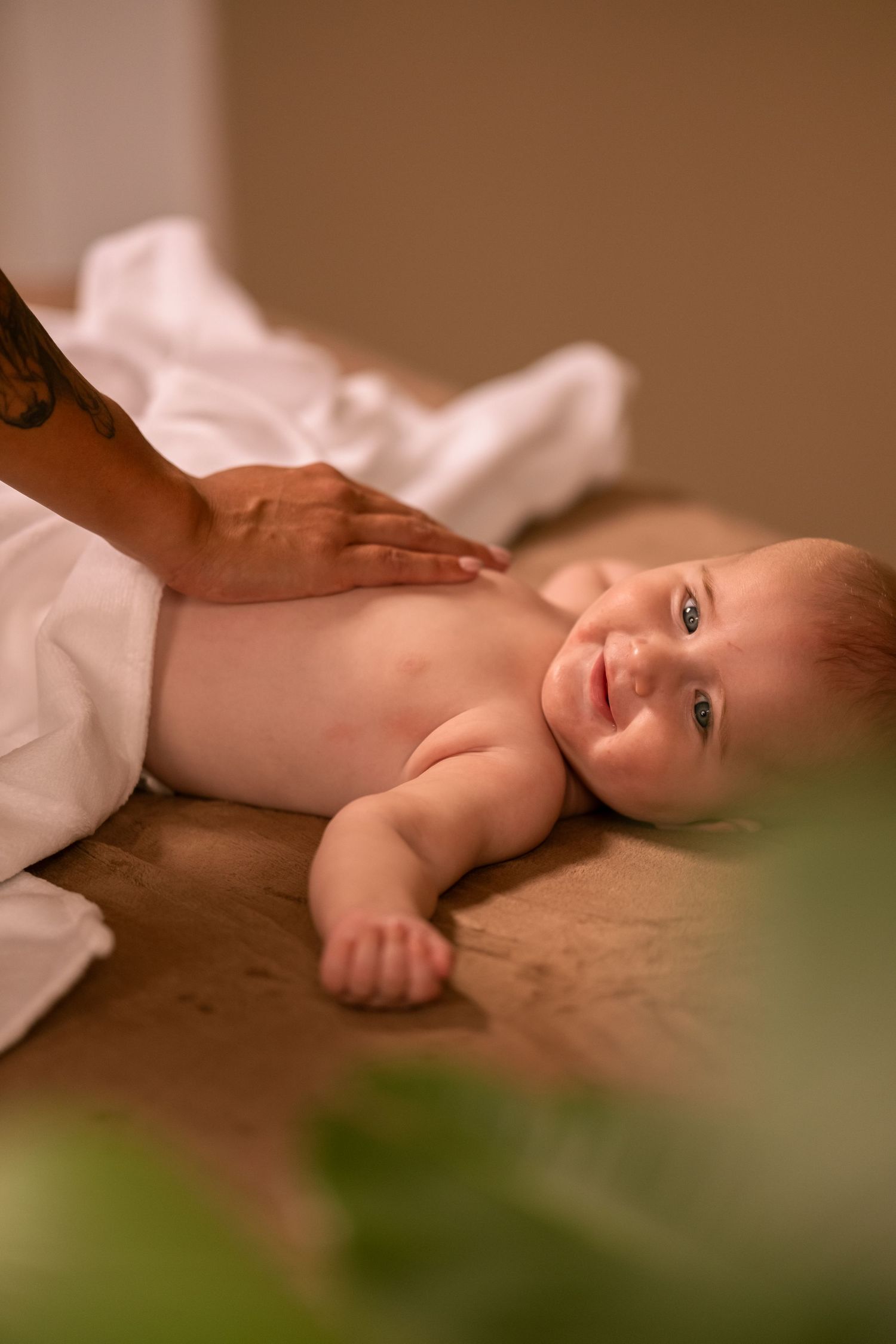 A gentle massage being given to a baby lying on a soft surface.
