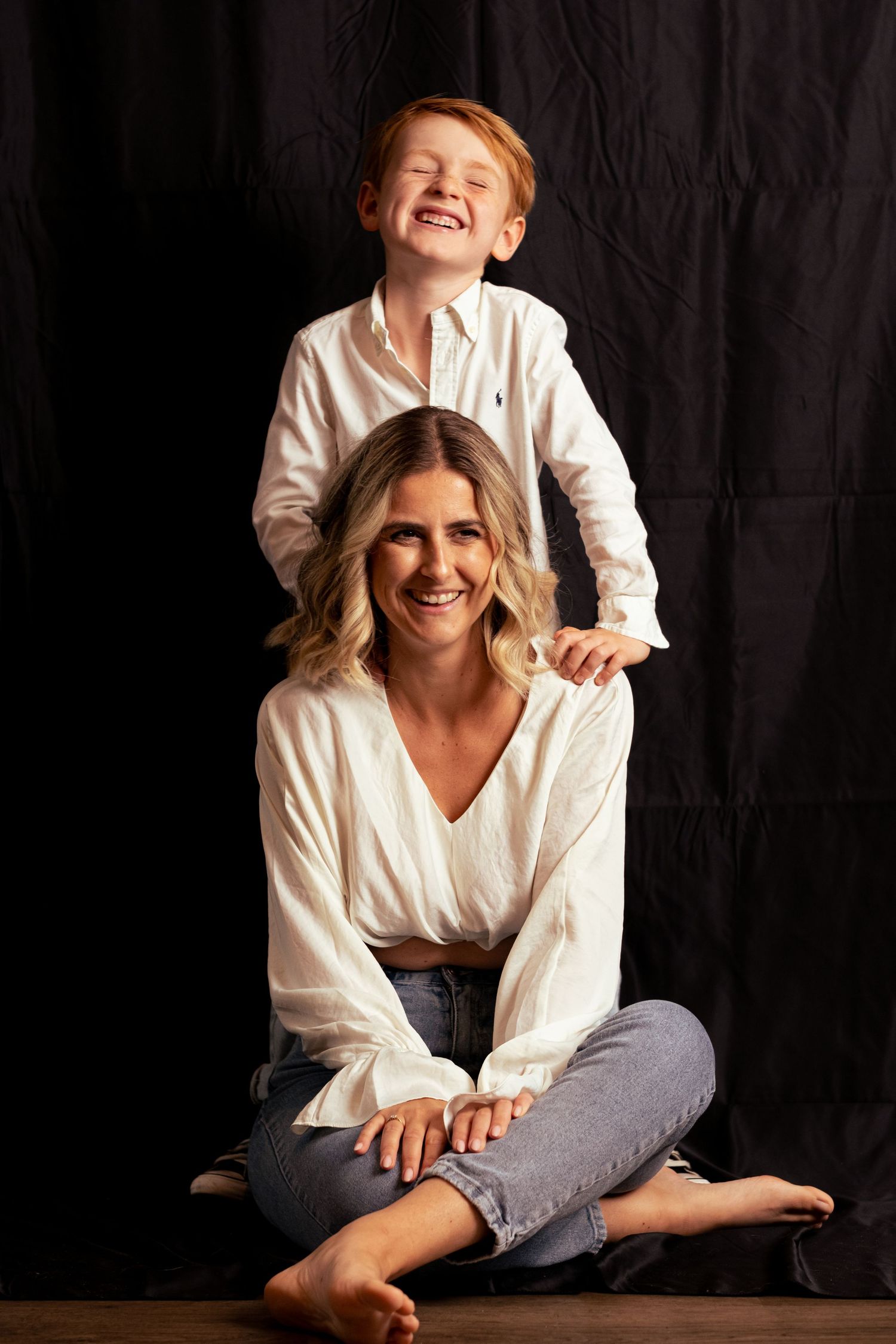 Candid lifestyle photography session showing joyful interaction against dark backdrop.