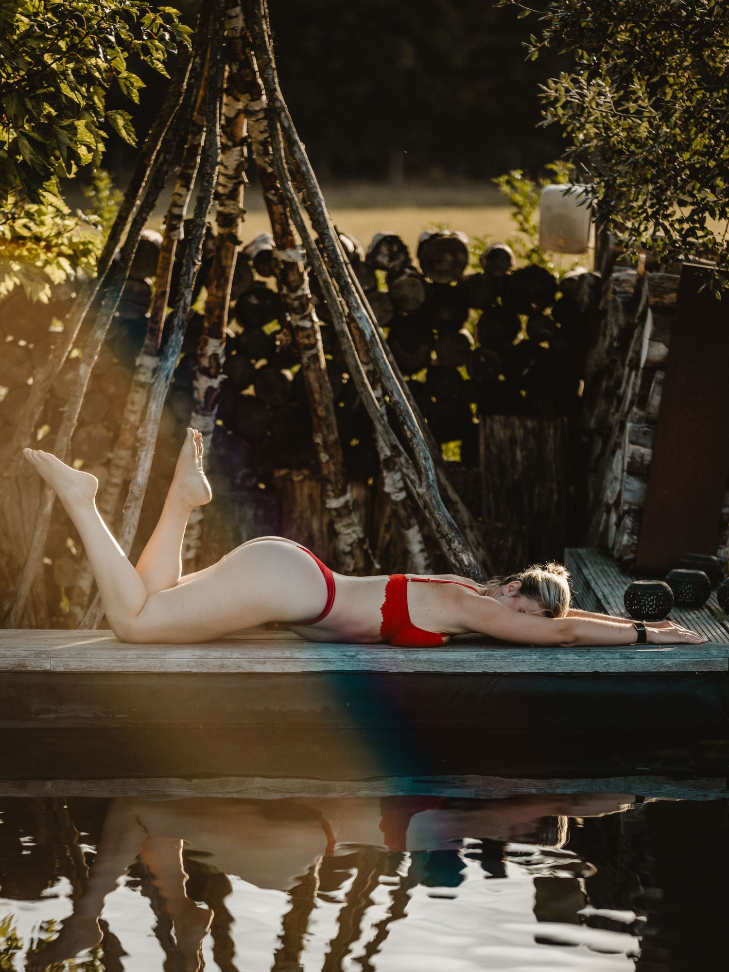 Poolside relaxation scene with string lights and reflections at sunset.