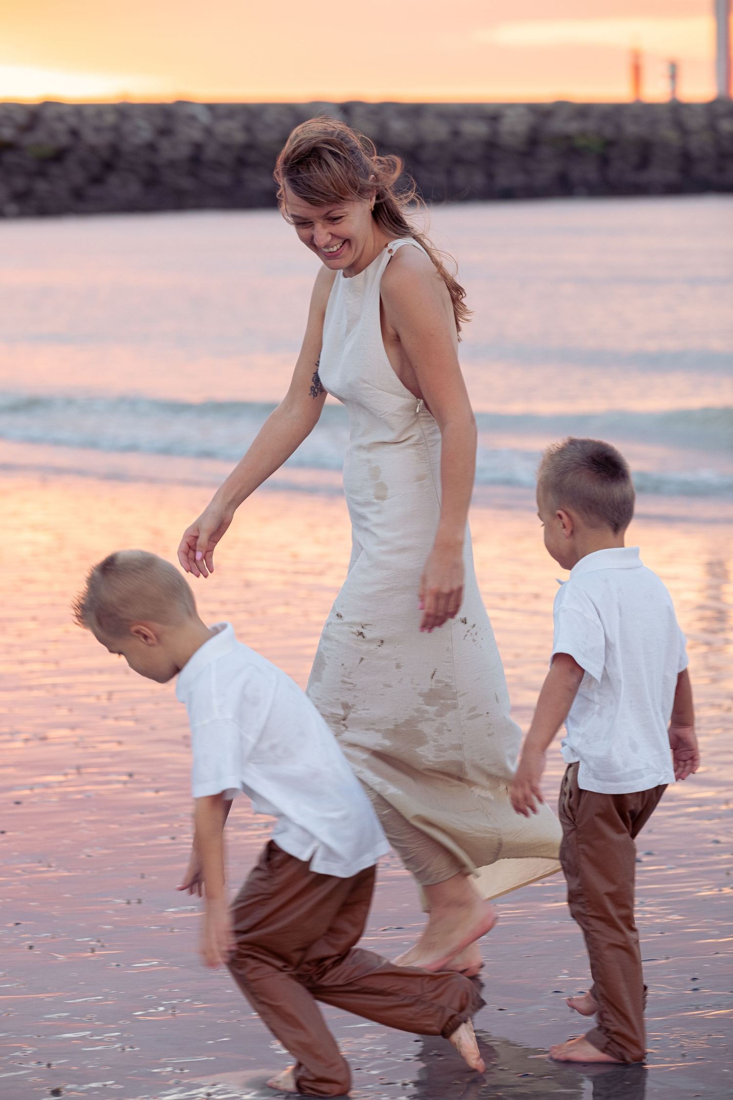 Children playing and splashing in shallow water at sunset on the beach.