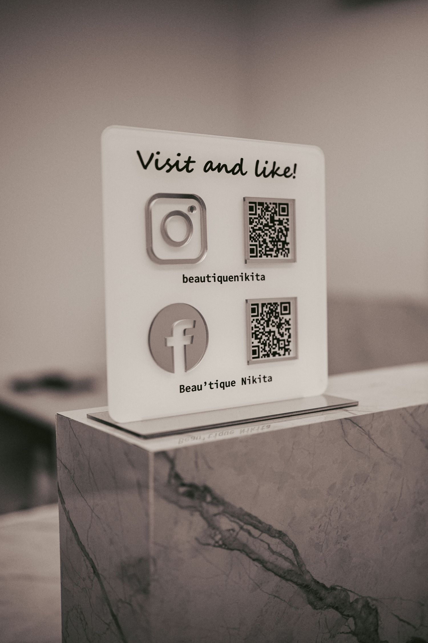White business cards with QR codes and social media icons displayed on a textured surface.