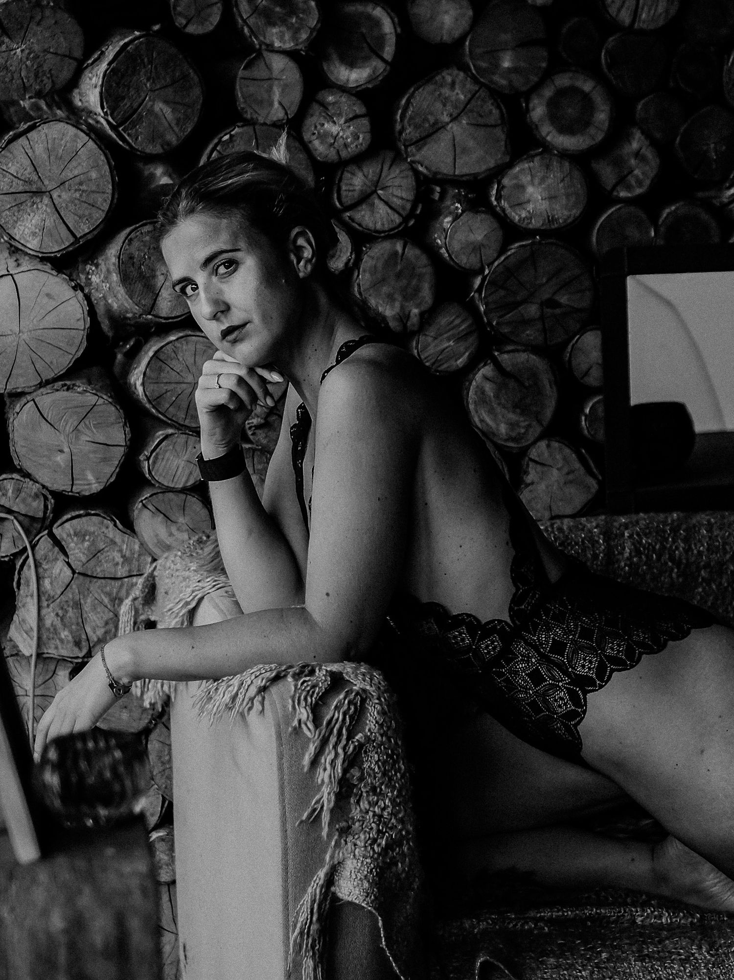 Artistic boudoir portrait against stacked firewood background.