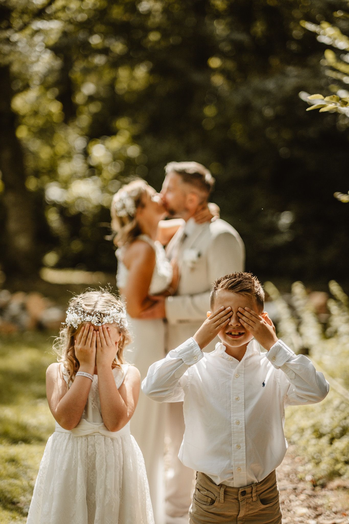 Playful group photo with everyone covering their eyes in a sunlit garden setting.