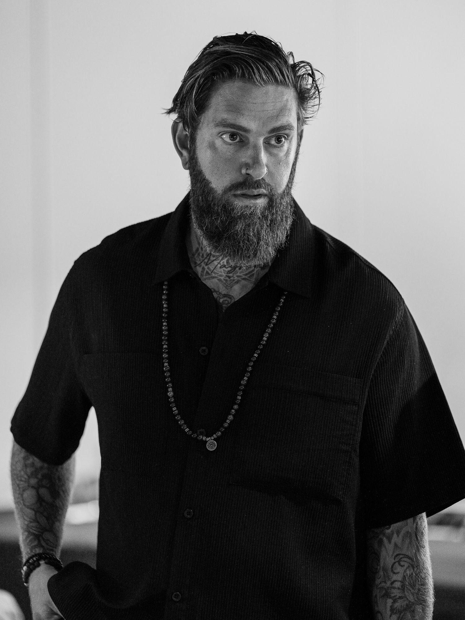 Portrait series of a bearded man in black clothing against white background.