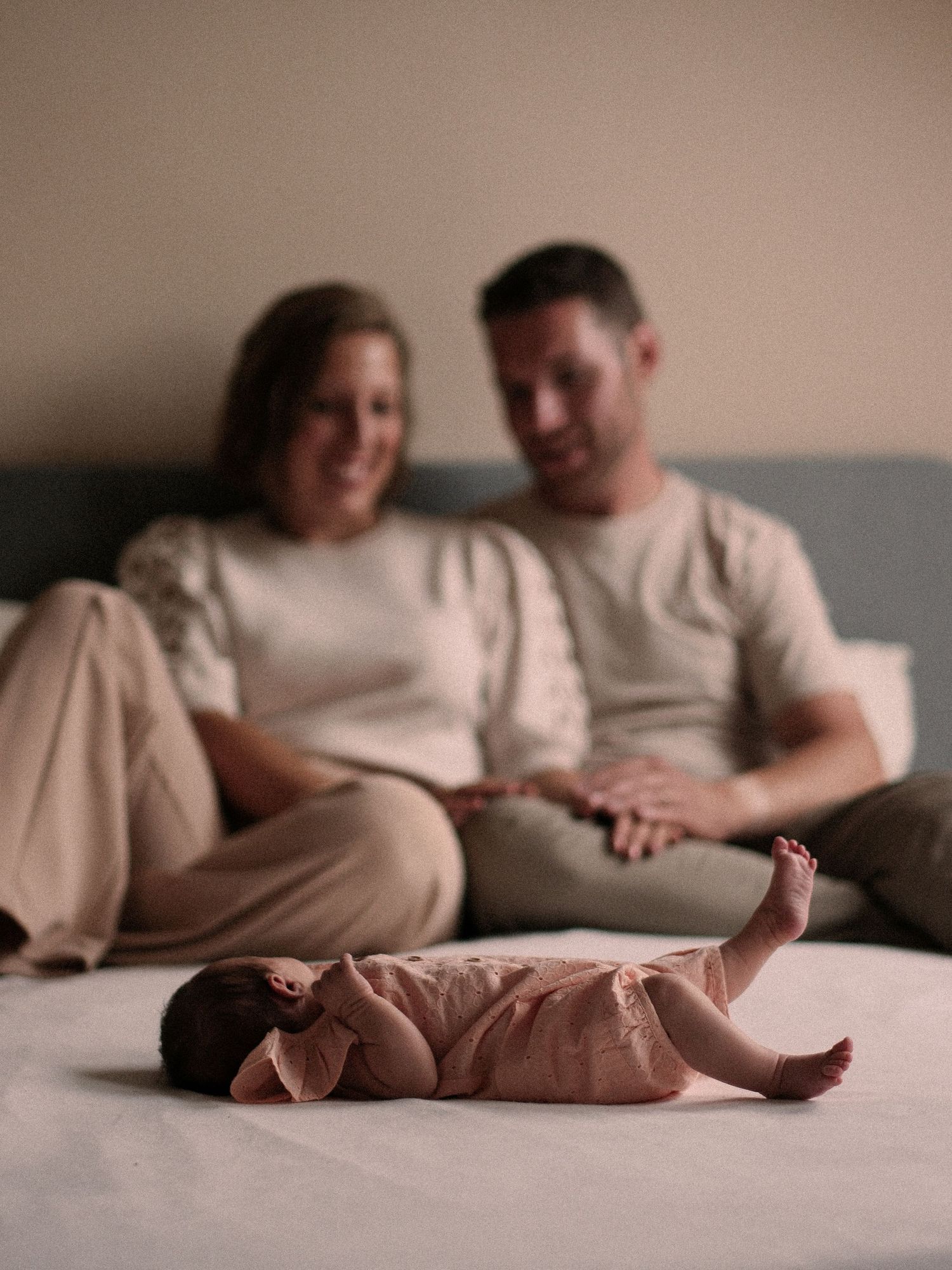 Intimate couple lounging on grey sofa with bare feet visible.