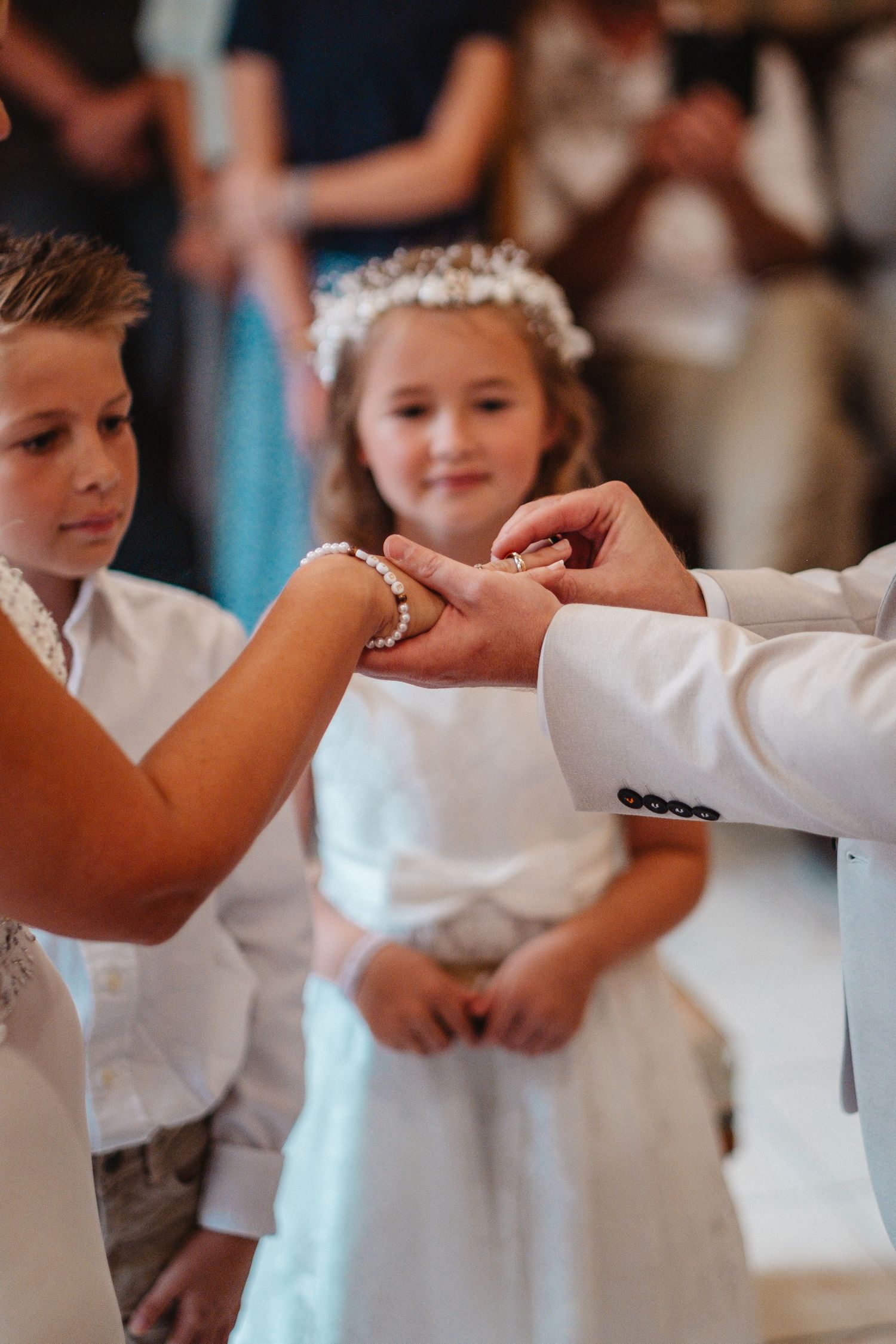Children in white formal attire hold hands in a circle during a wedding celebration.