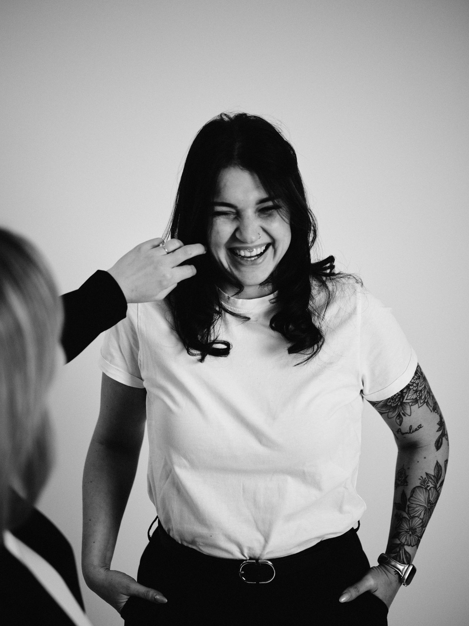 Black and white photo series showing a person in a white t-shirt with tattoos expressing joyful emotions.