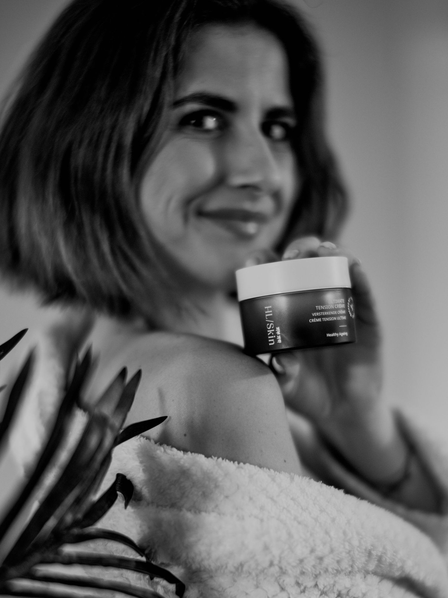 Black and white photo series showing a person with short hair smiling while holding a white container.