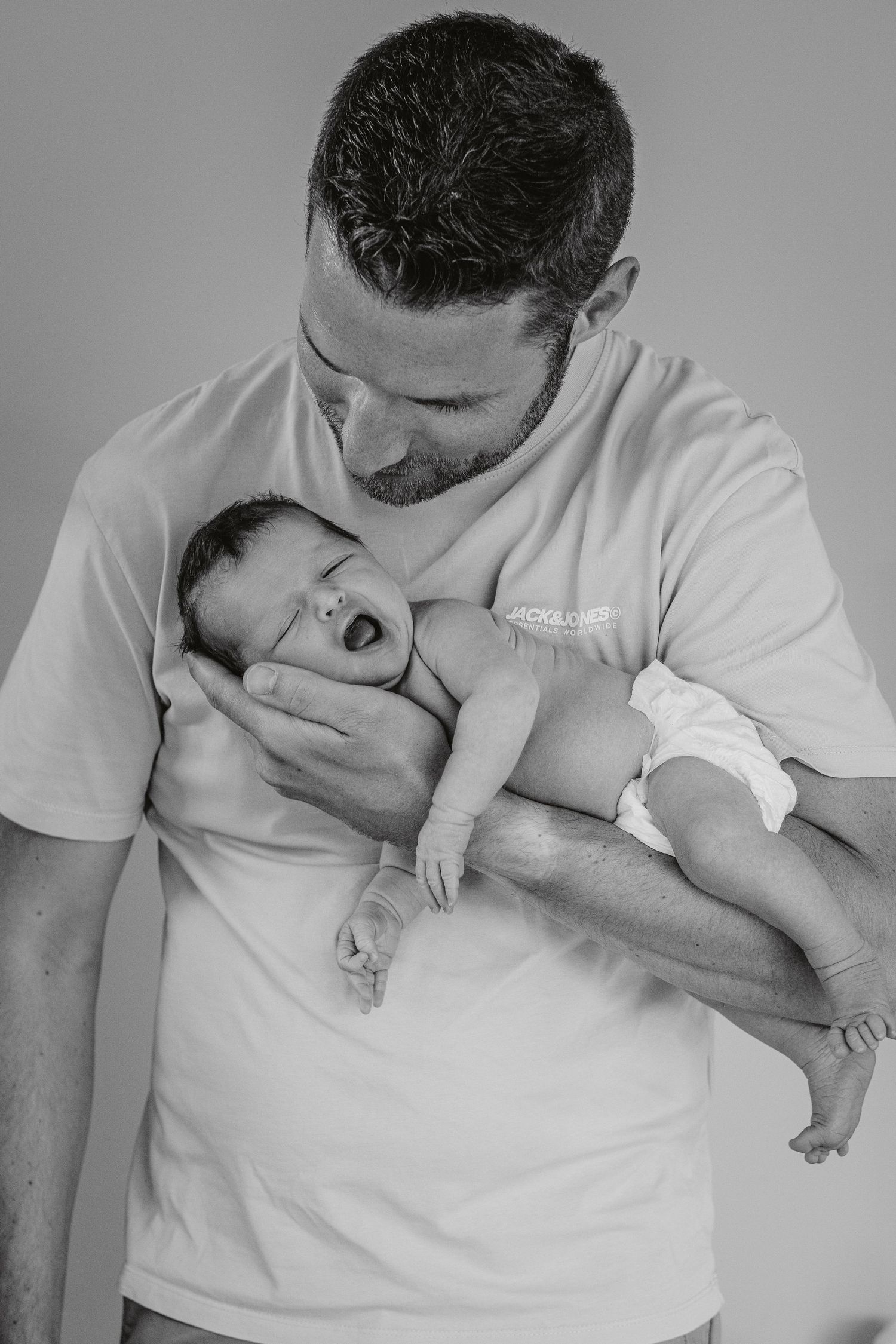 Series showing tender interaction between parent in white shirt and newborn baby.