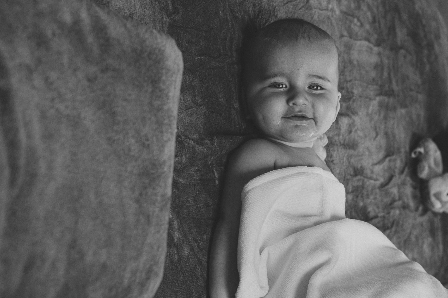 Black and white portrait series of infant against textured wall background.