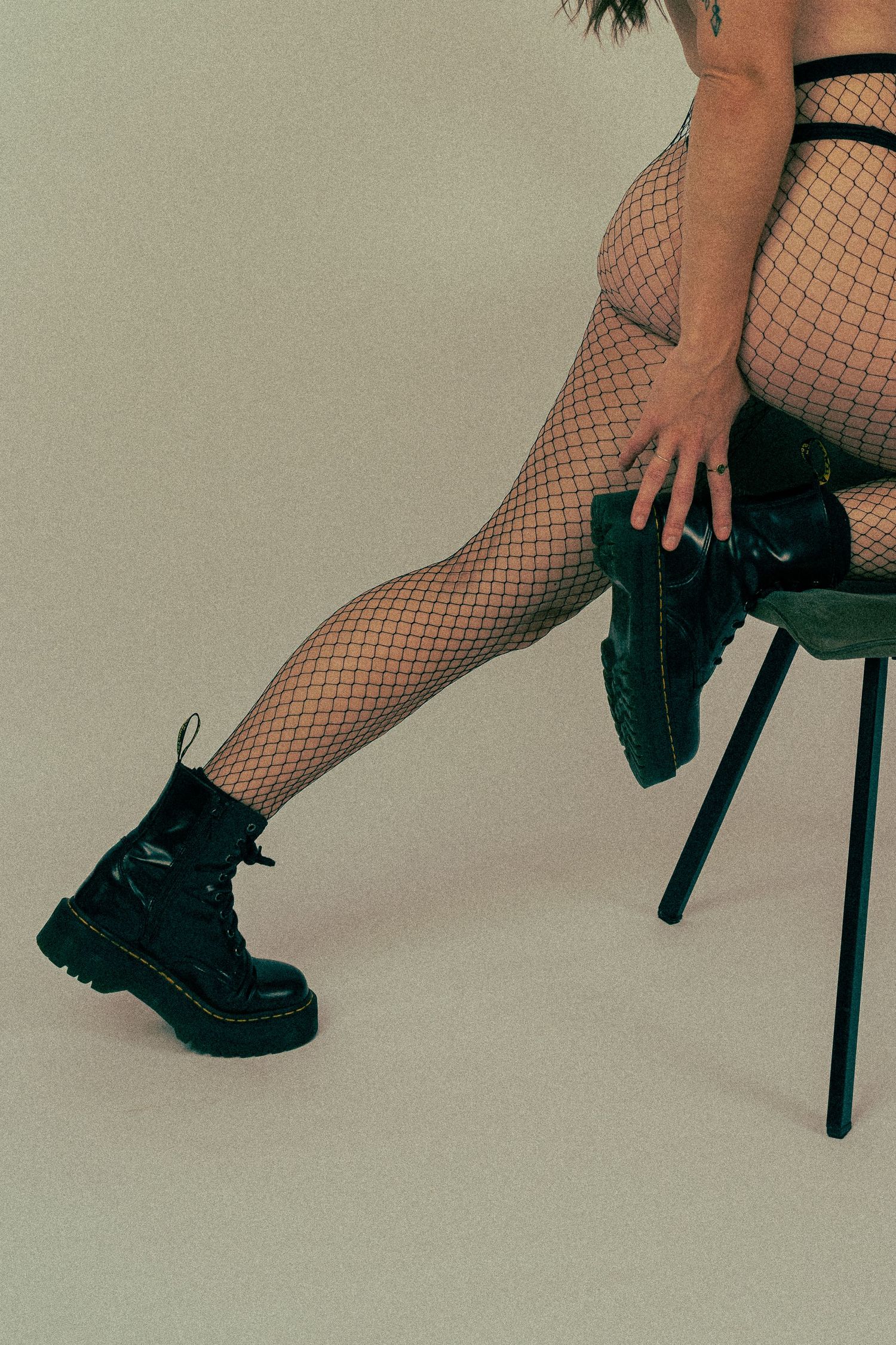 Legs wearing chunky black boots and fishnet stockings on a chair.
