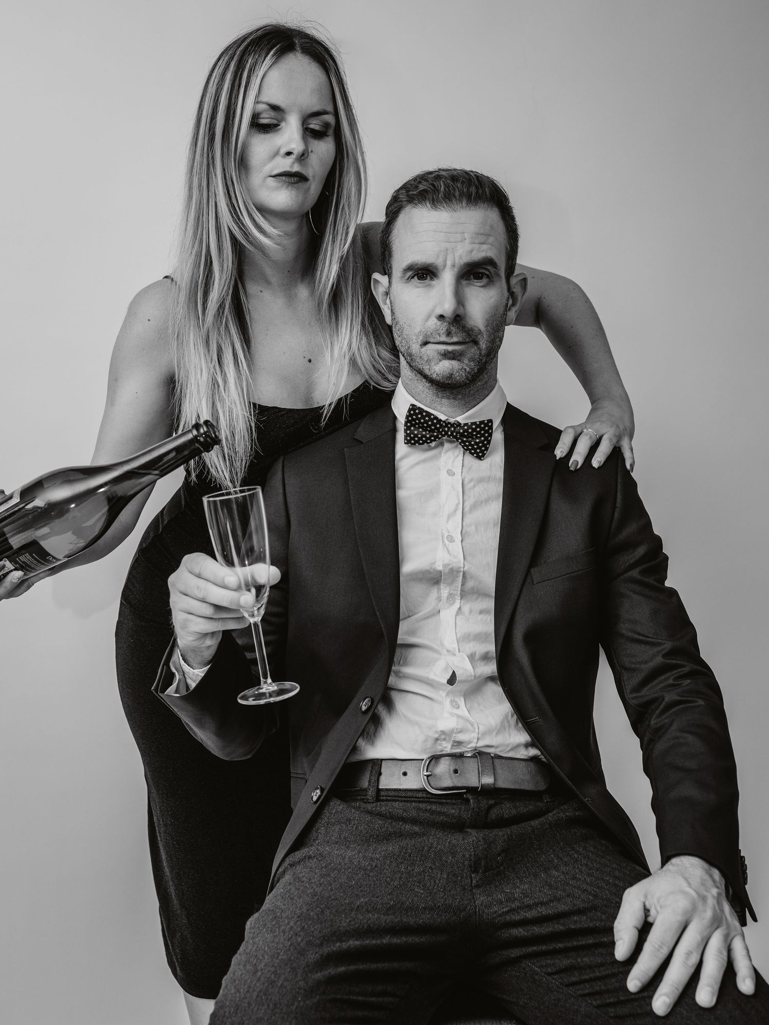 A stylish black and white photo series showing a couple in formal attire sharing champagne and intimate moments.