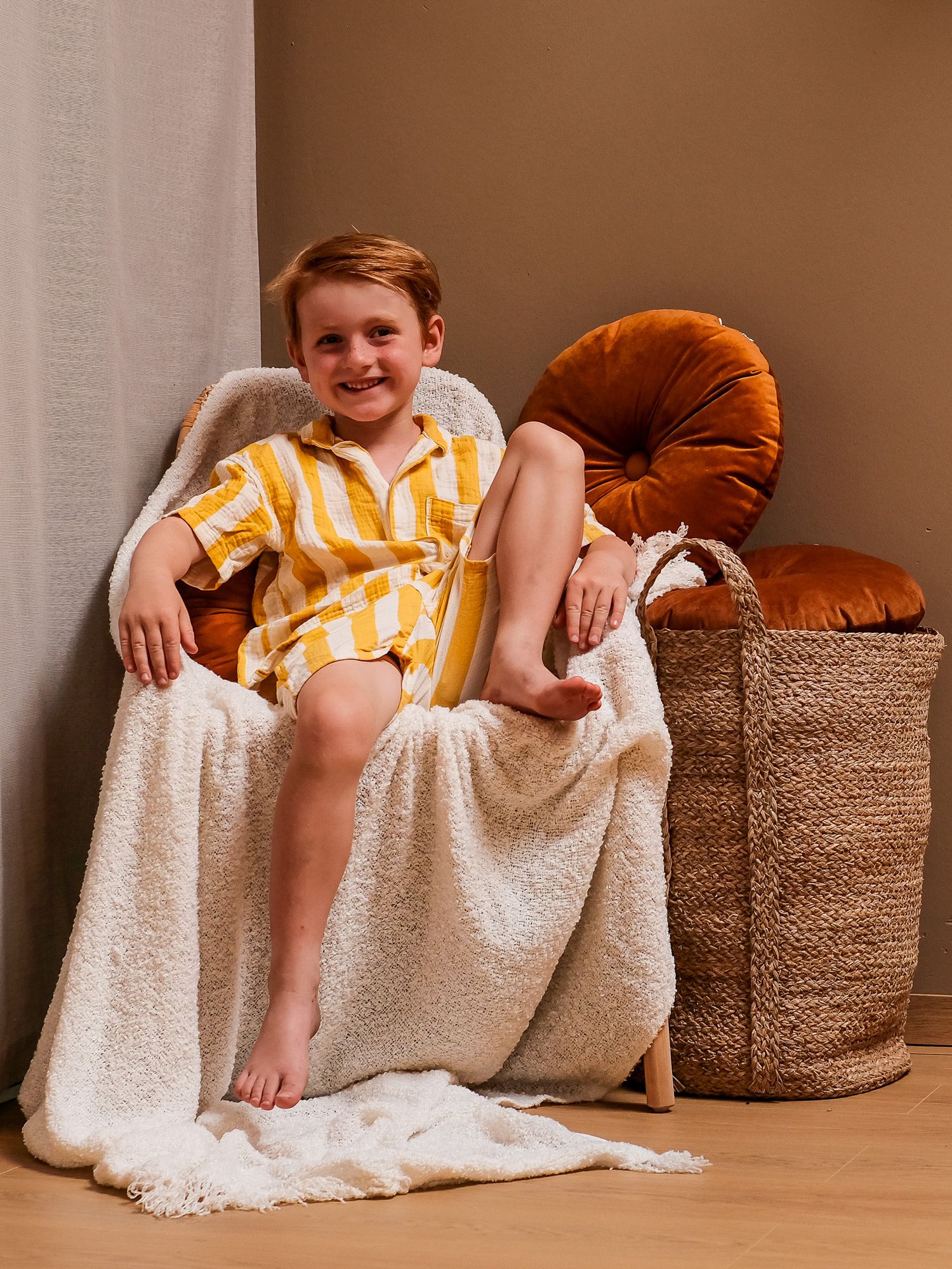 Cozy lifestyle photos with person relaxing on cushions with white throw blanket.