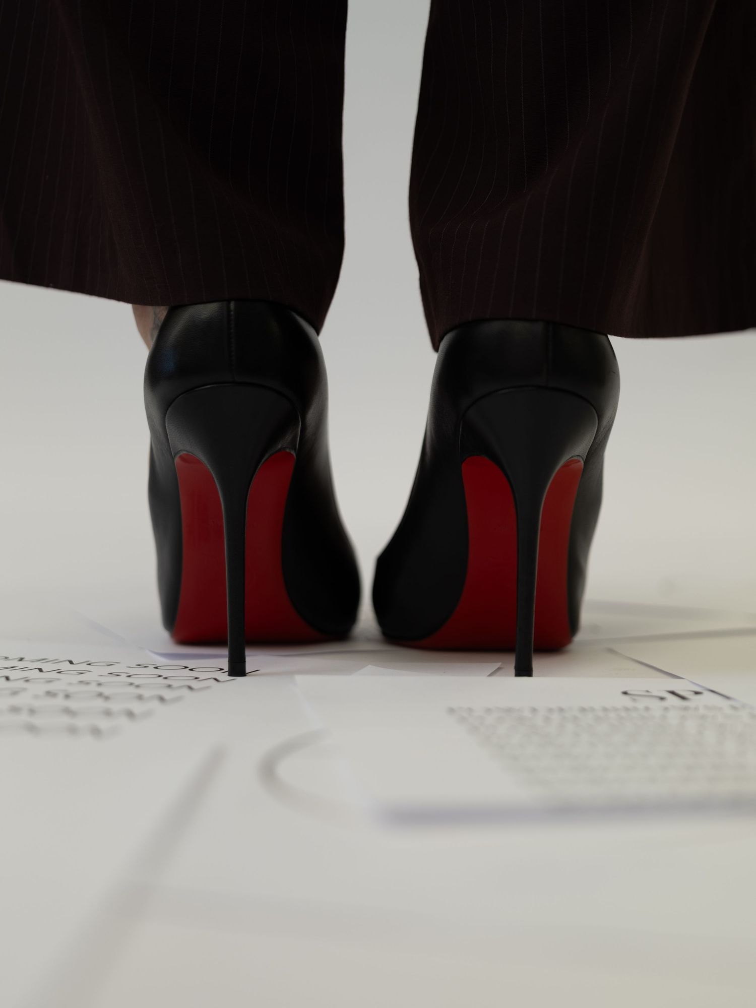 A series of black high heels with distinctive red soles shown from different angles on a white surface.