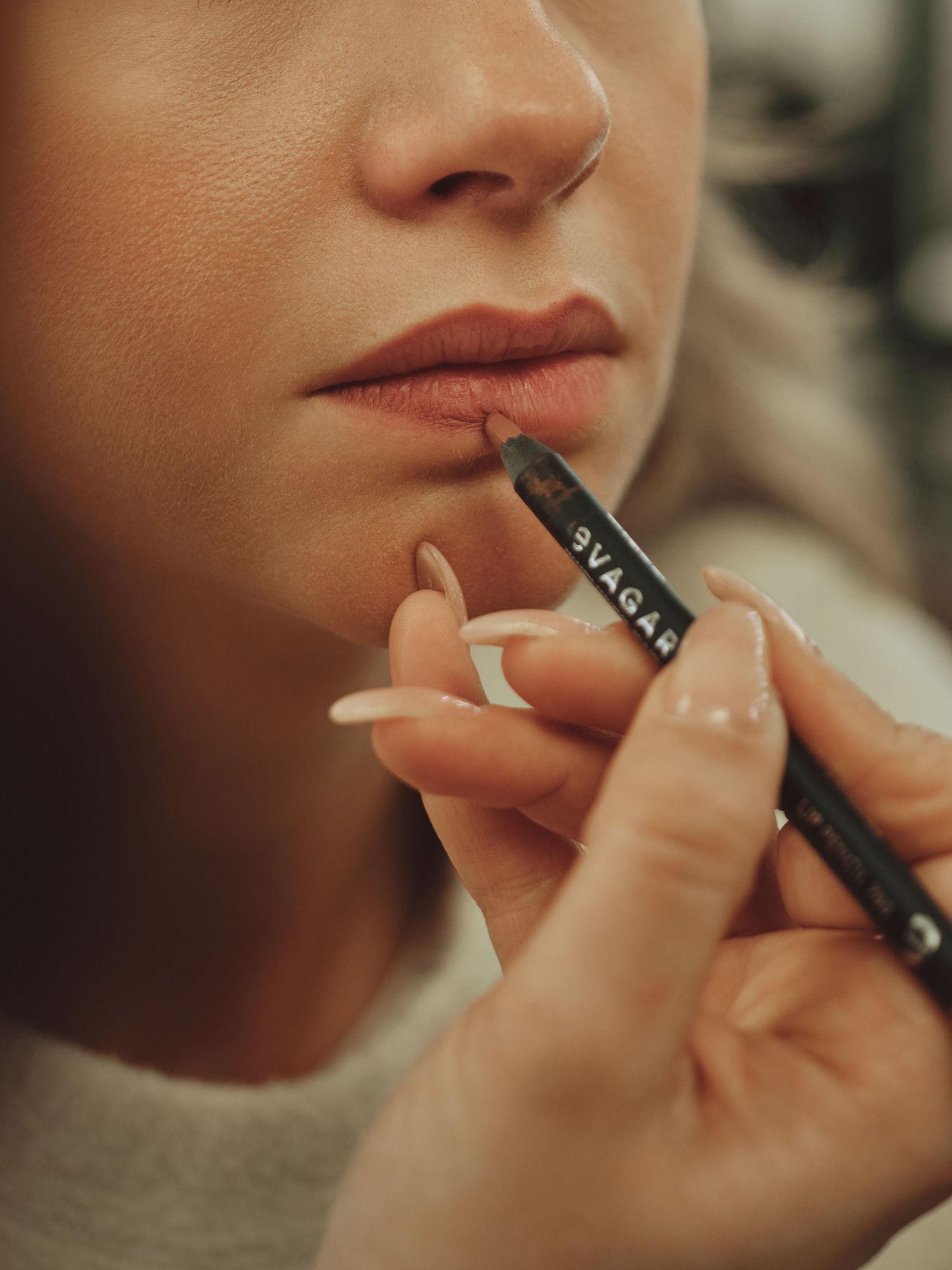 A makeup artist applies a SVAGAR lip liner pencil to a woman's lips for precise definition.