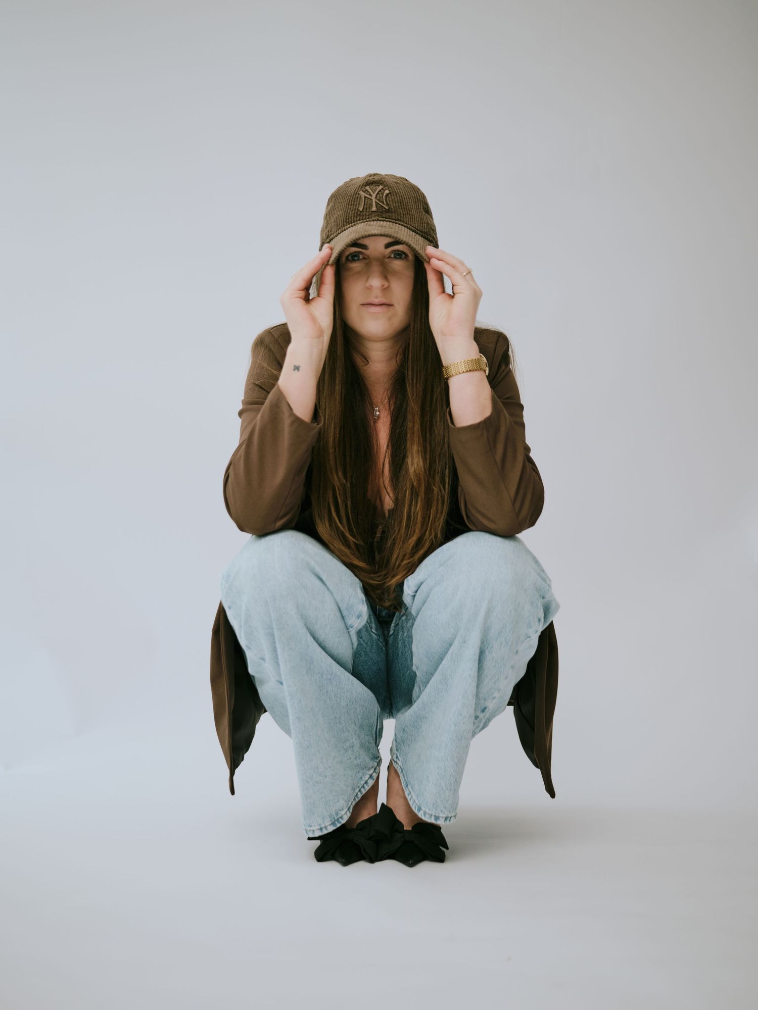A person in a brown jacket and beanie strikes different poses against a white background in a photo series.