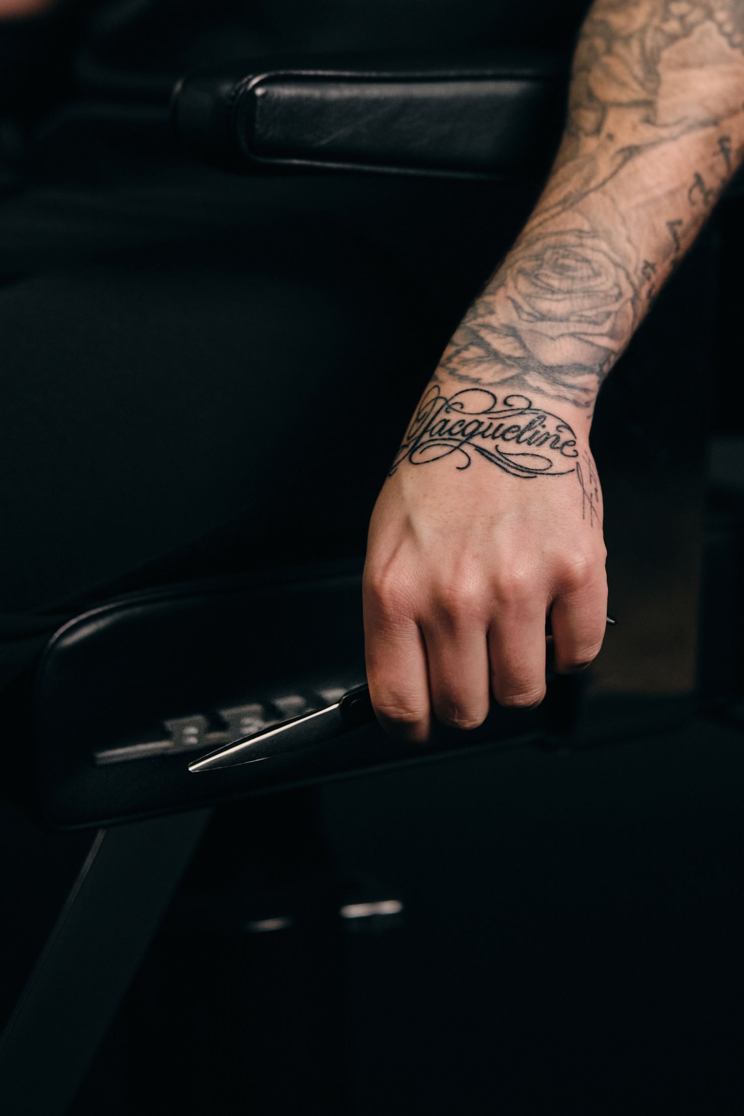 Close-up shots of tattooed hands gripping a black motorcycle handlebar in dark lighting.
