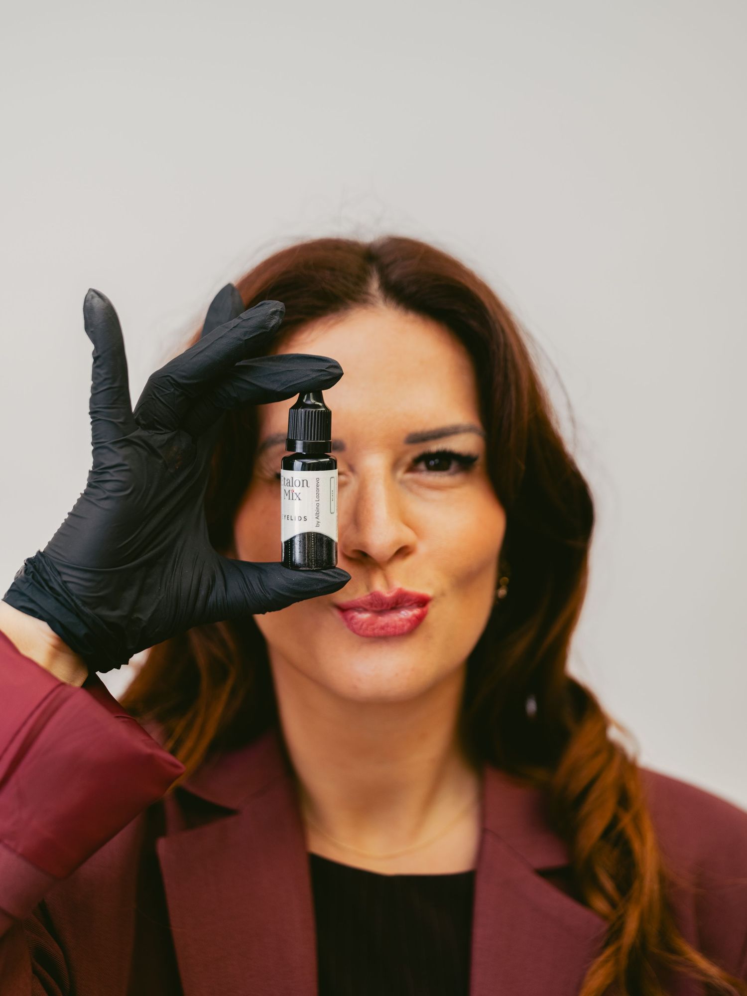 A person wearing black gloves and a burgundy blazer shows different playful expressions in a four-panel photo series.