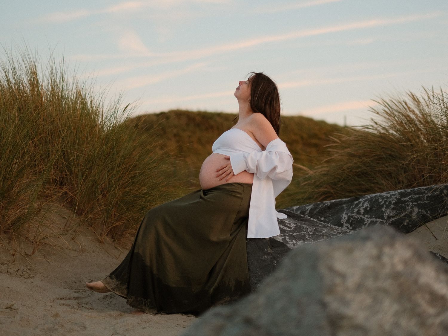Romantic beach scene with couple silhouetted against coastal dunes at sunset.