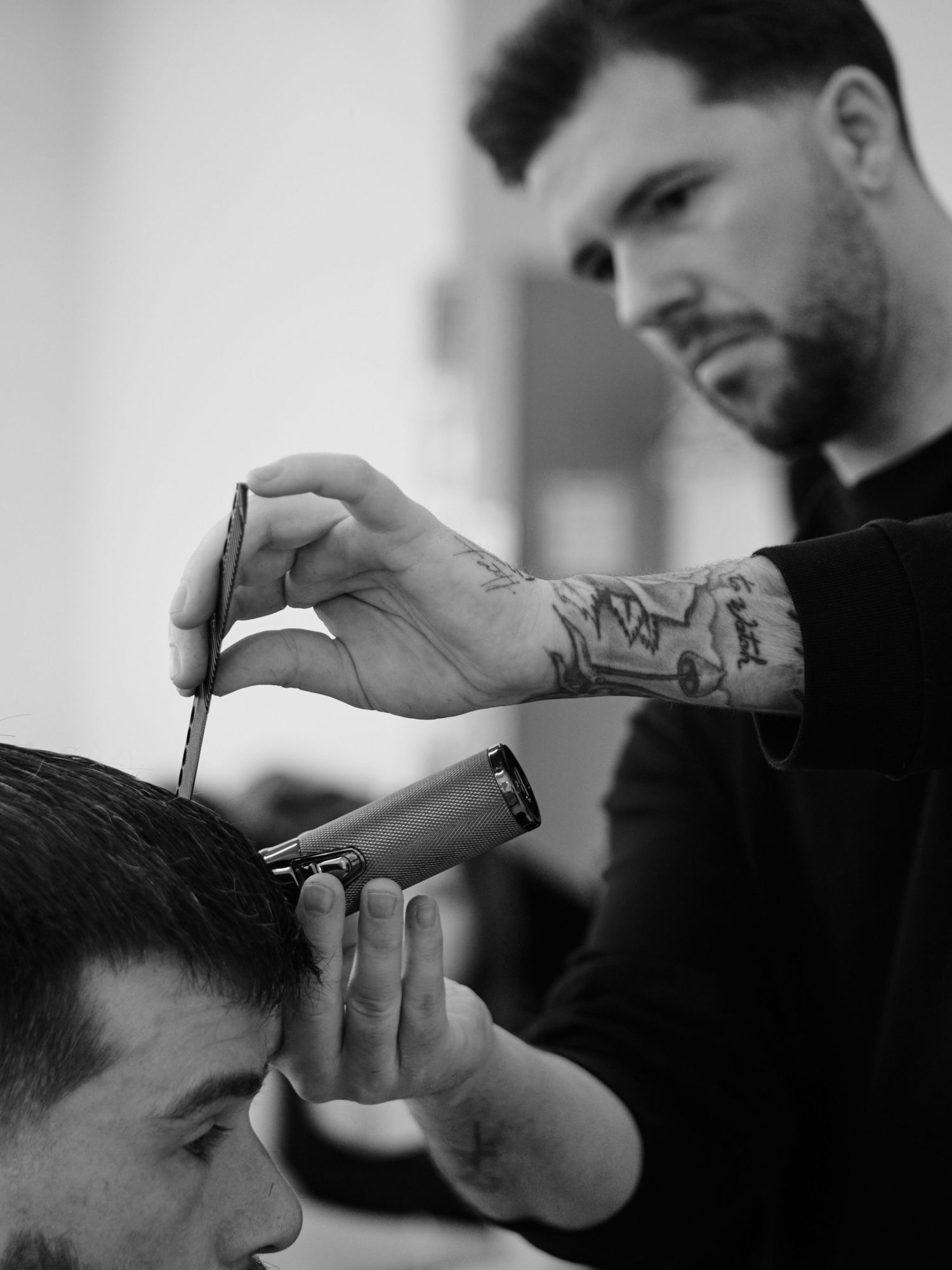 Professional barber using scissors and comb to trim and style hair in a modern barbershop setting.