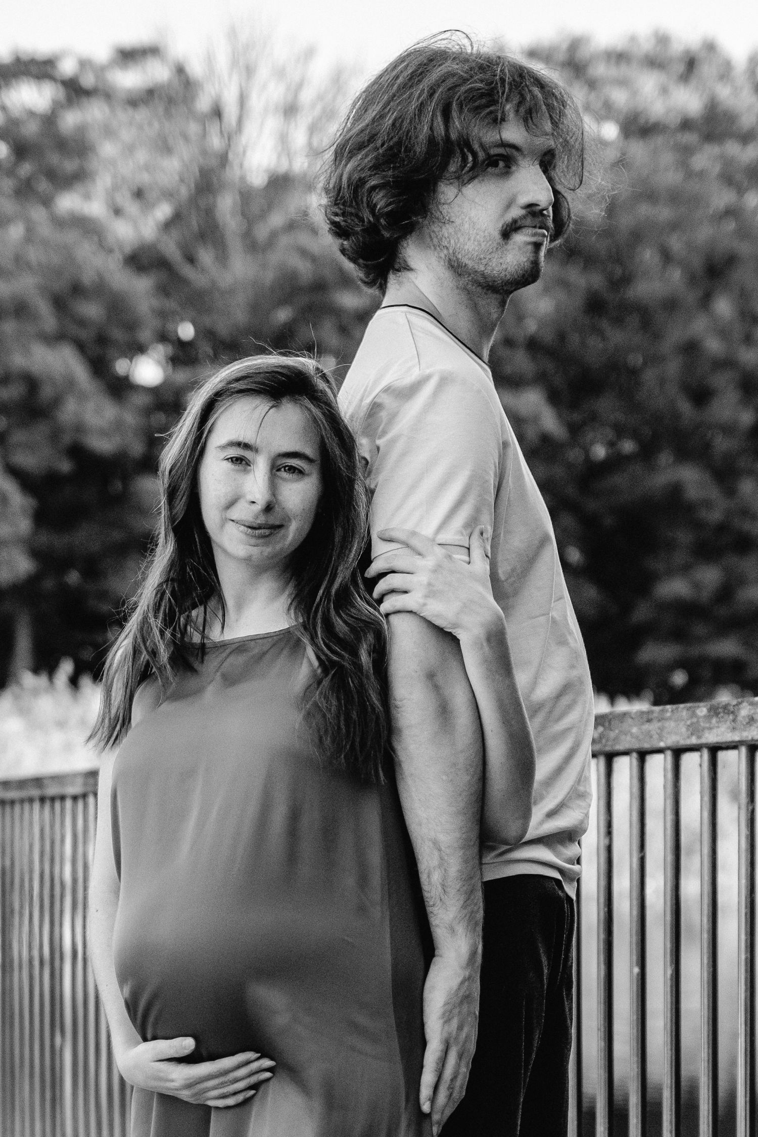 Black and white maternity portraits taken on a wooden deck with natural expressions.