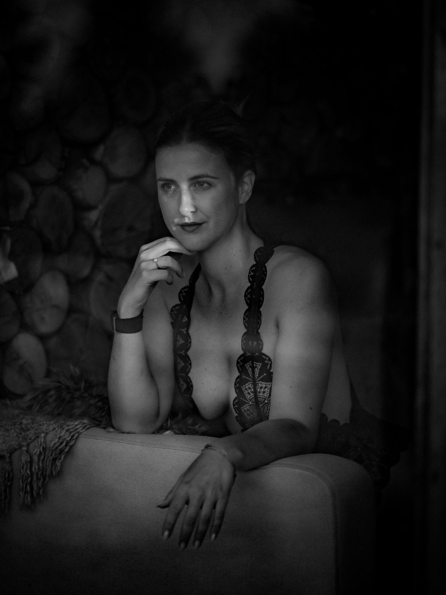 Artistic black and white boudoir portrait with dramatic lighting and intimate mood against dark background.