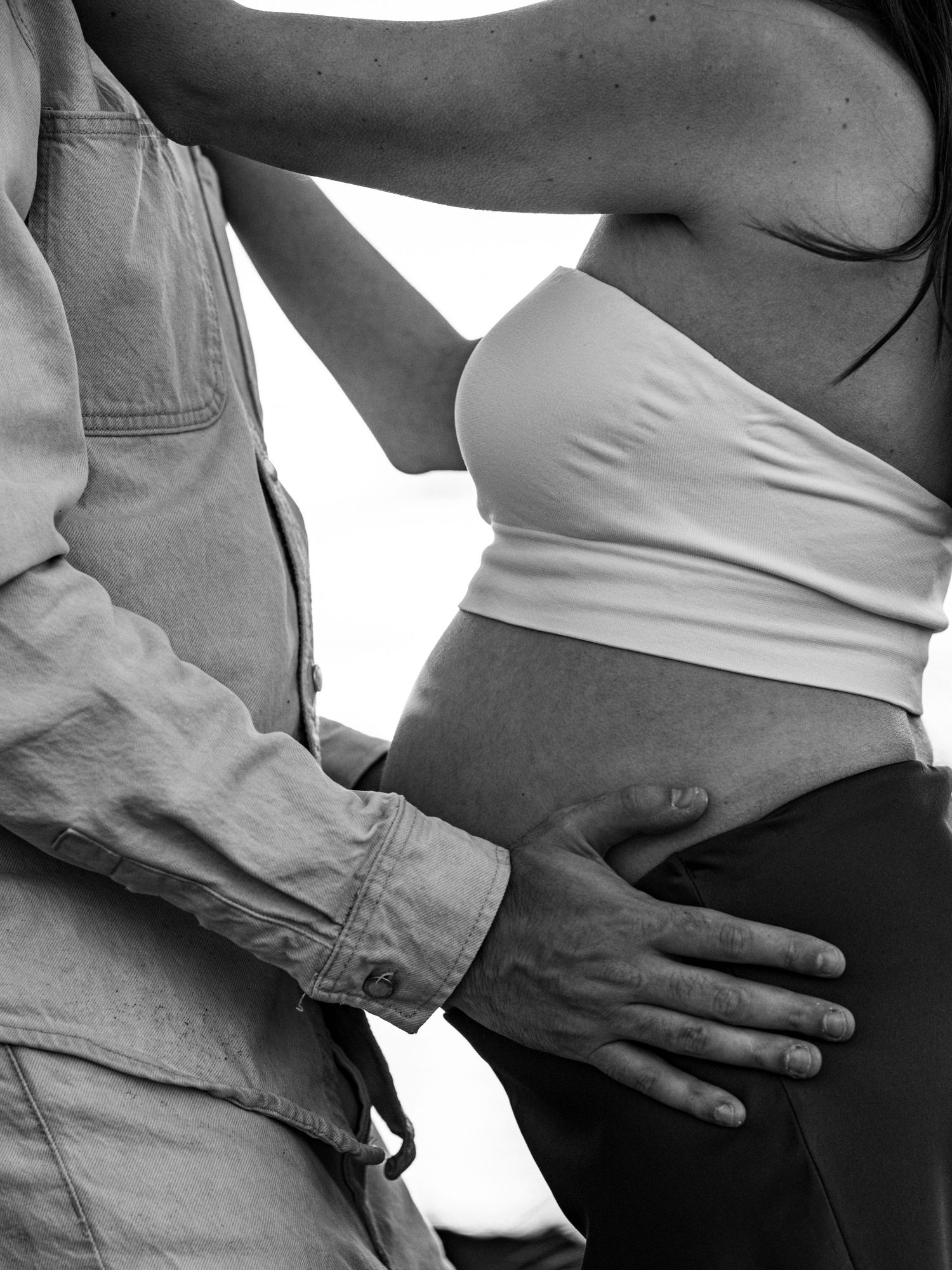 Black and white close-up series showing gentle hands cradling a pregnant belly.