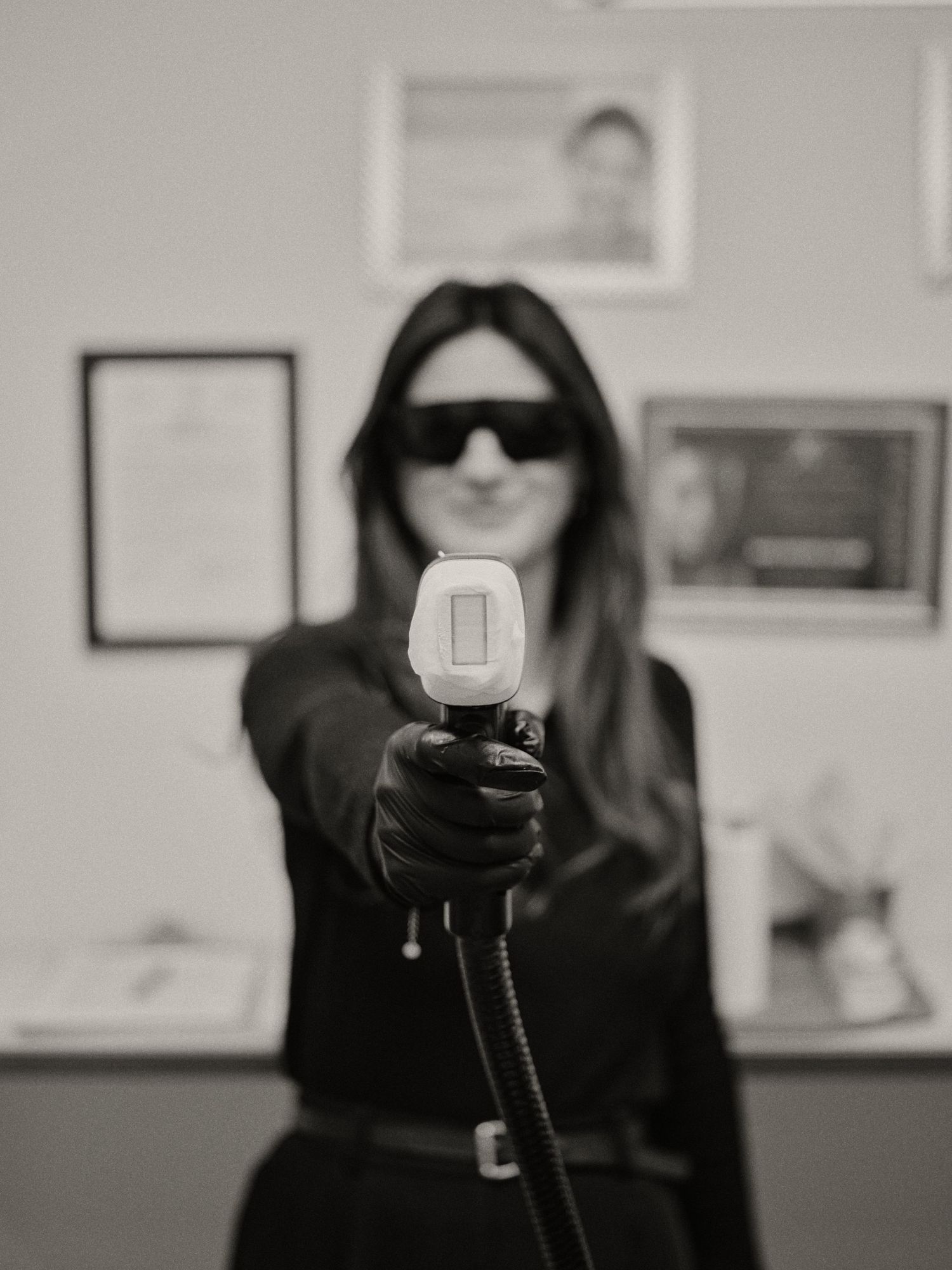 A black and white photo series showing someone in dark clothing and sunglasses posing against a white wall.