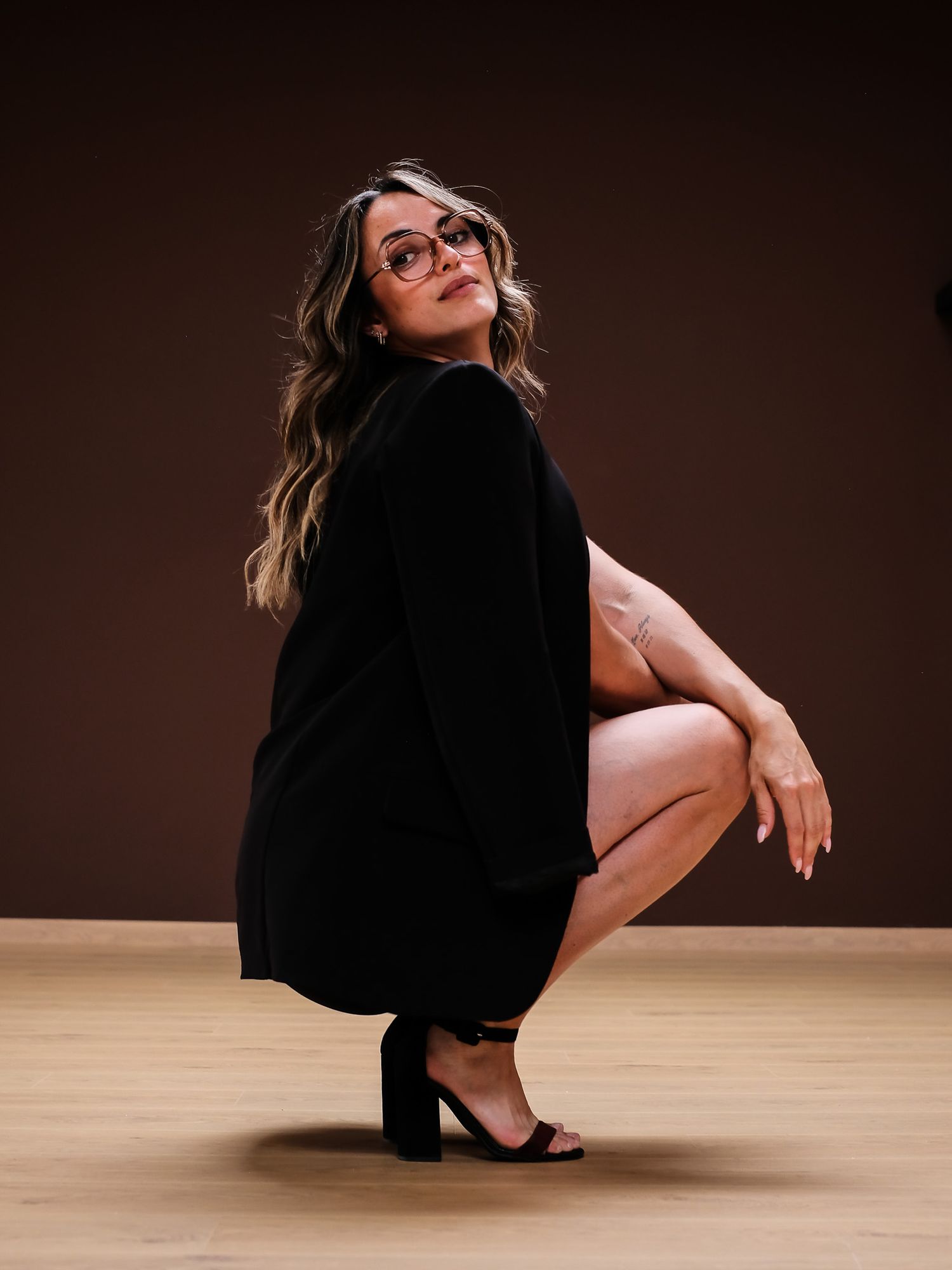 A sequence showing a person in black clothing gracefully rolling on a wooden floor against a dark background.