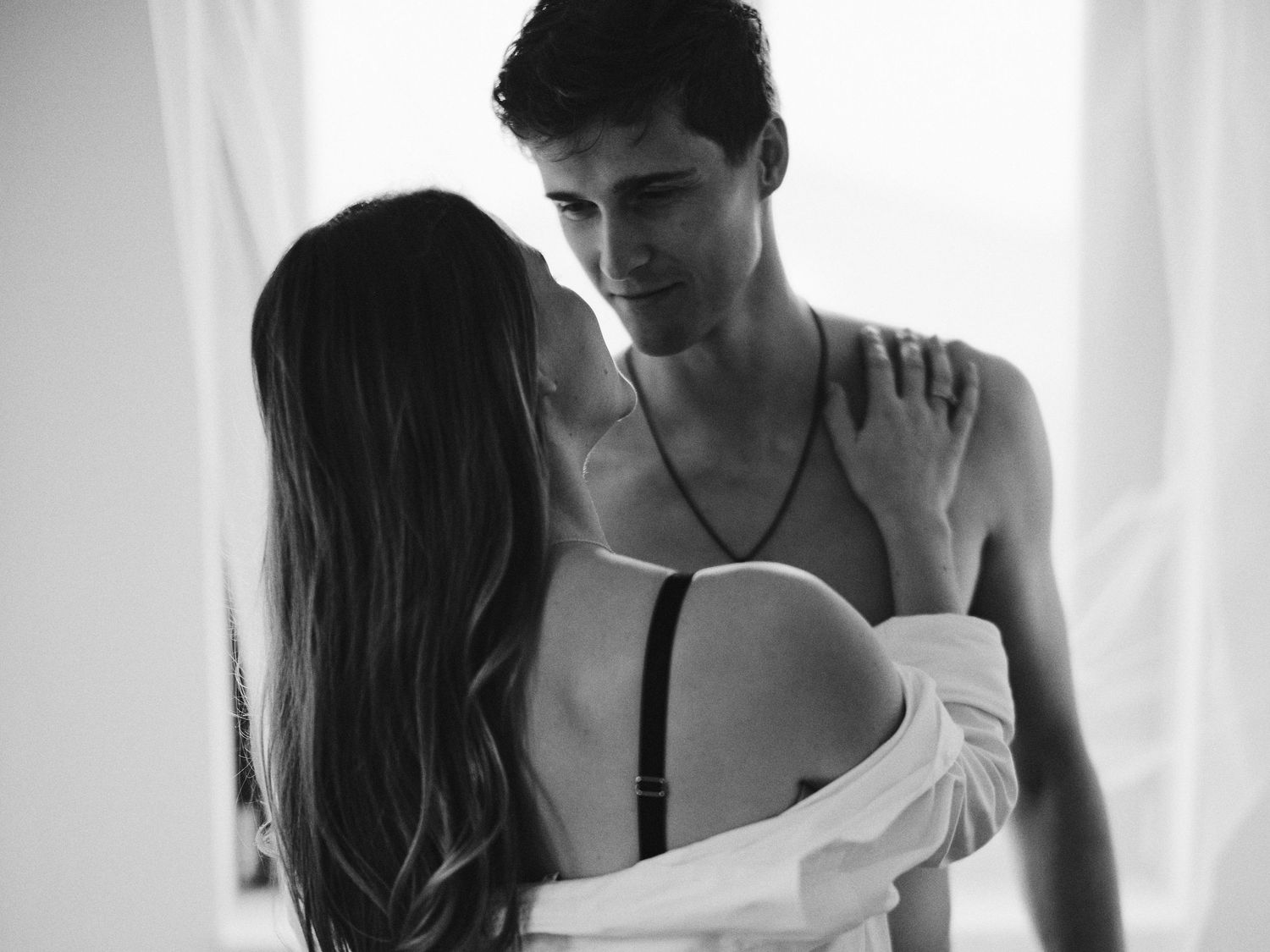A series of romantic black and white photos showing tender moments between a couple embracing near a window.