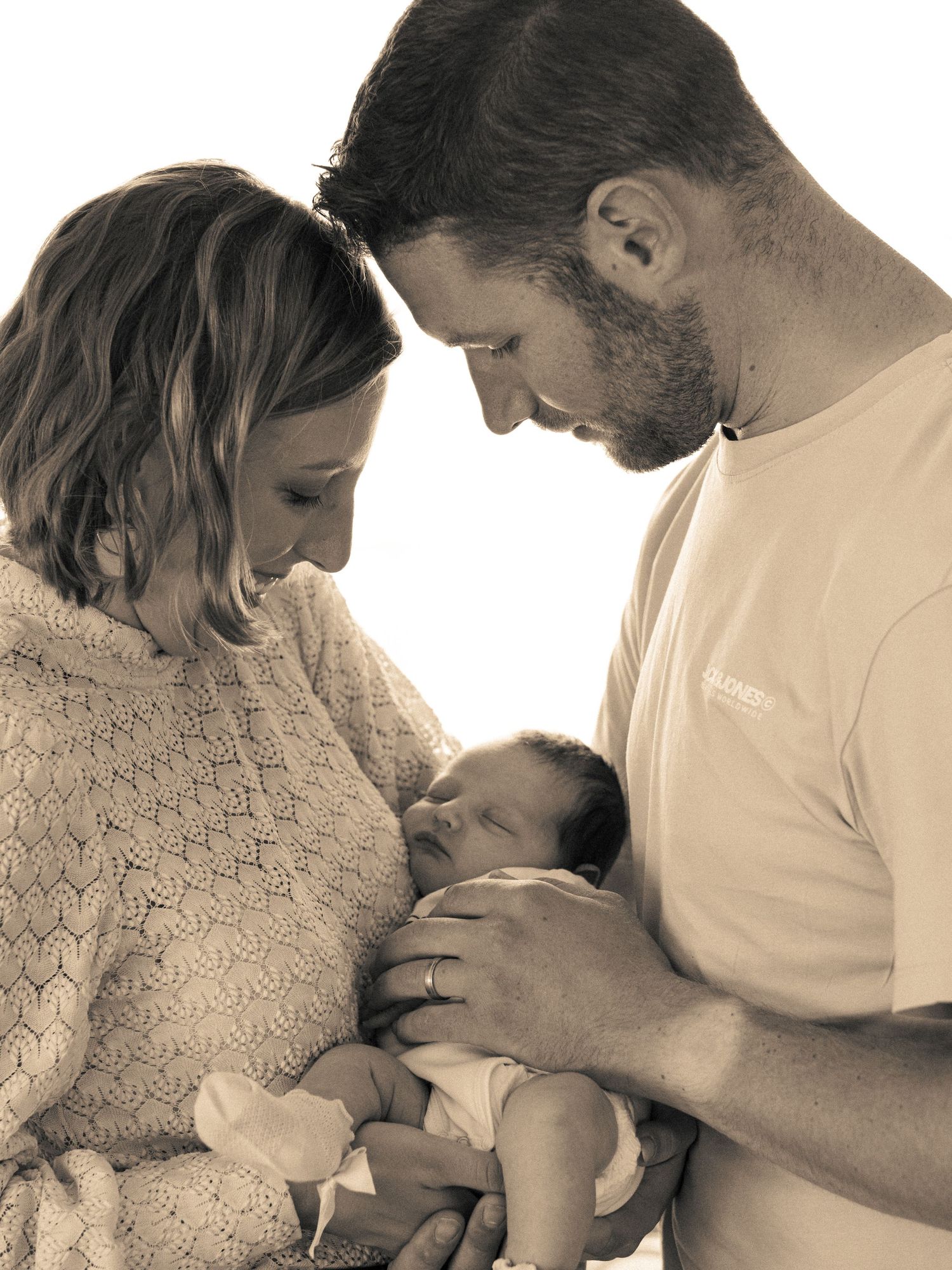 Family sharing tender moments with newborn baby in black and white photography.