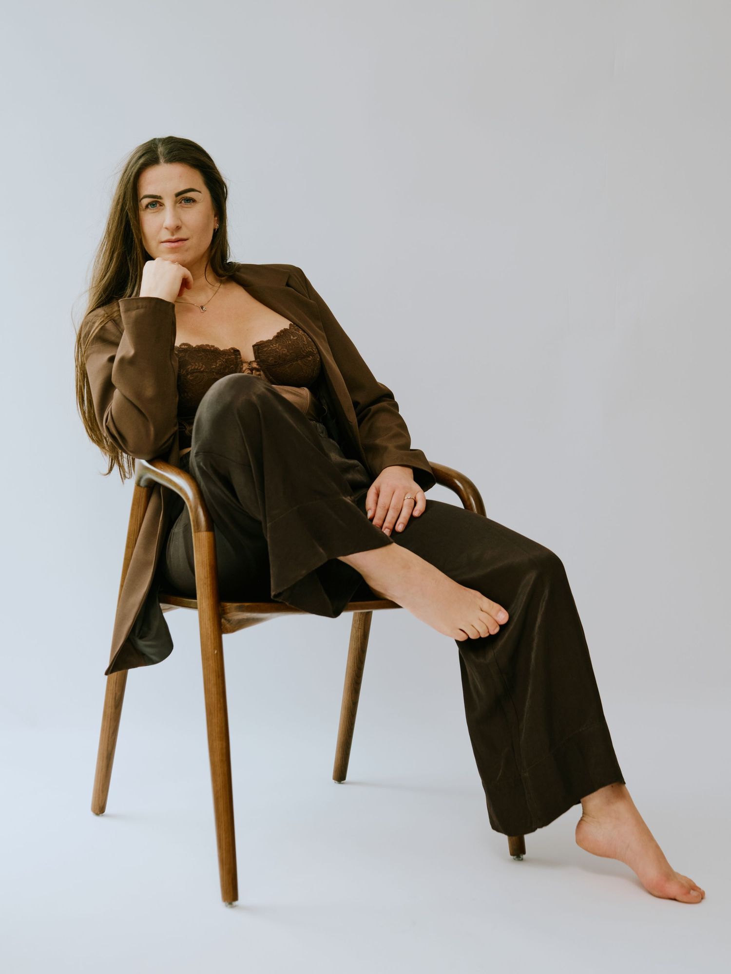 A series of fashion photographs showing a model in a brown outfit posing on a wooden chair against a light gray backdrop.