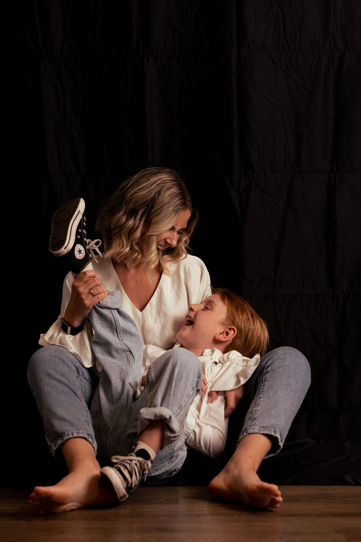 Lifestyle portrait of two people in white shirts lying on dark floor.