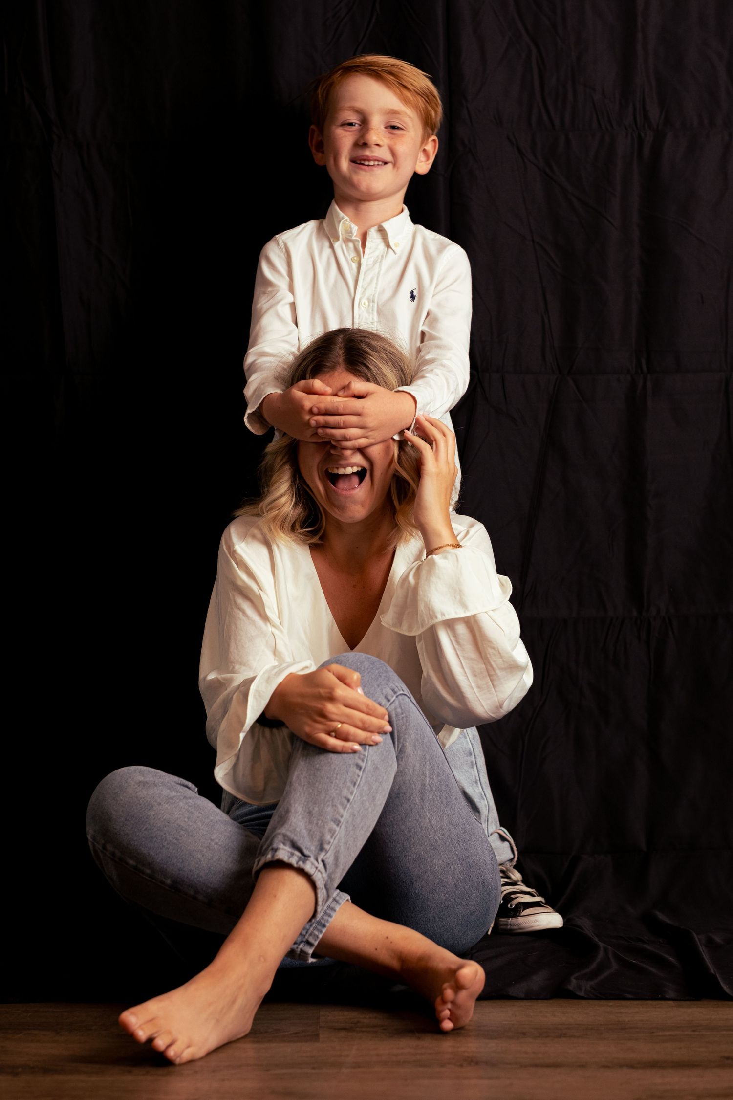 Playful portrait series showing interaction between two people against dark backdrop.