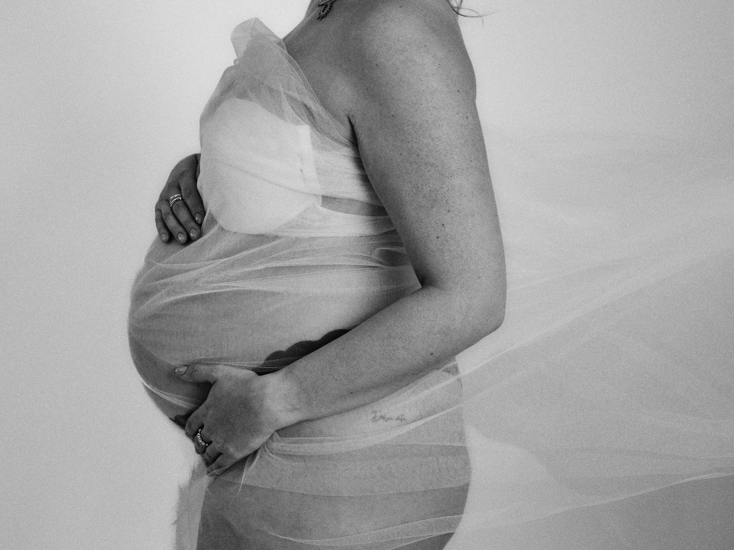 A black and white photo series showing the progression of a pregnant woman's growing belly over several months.