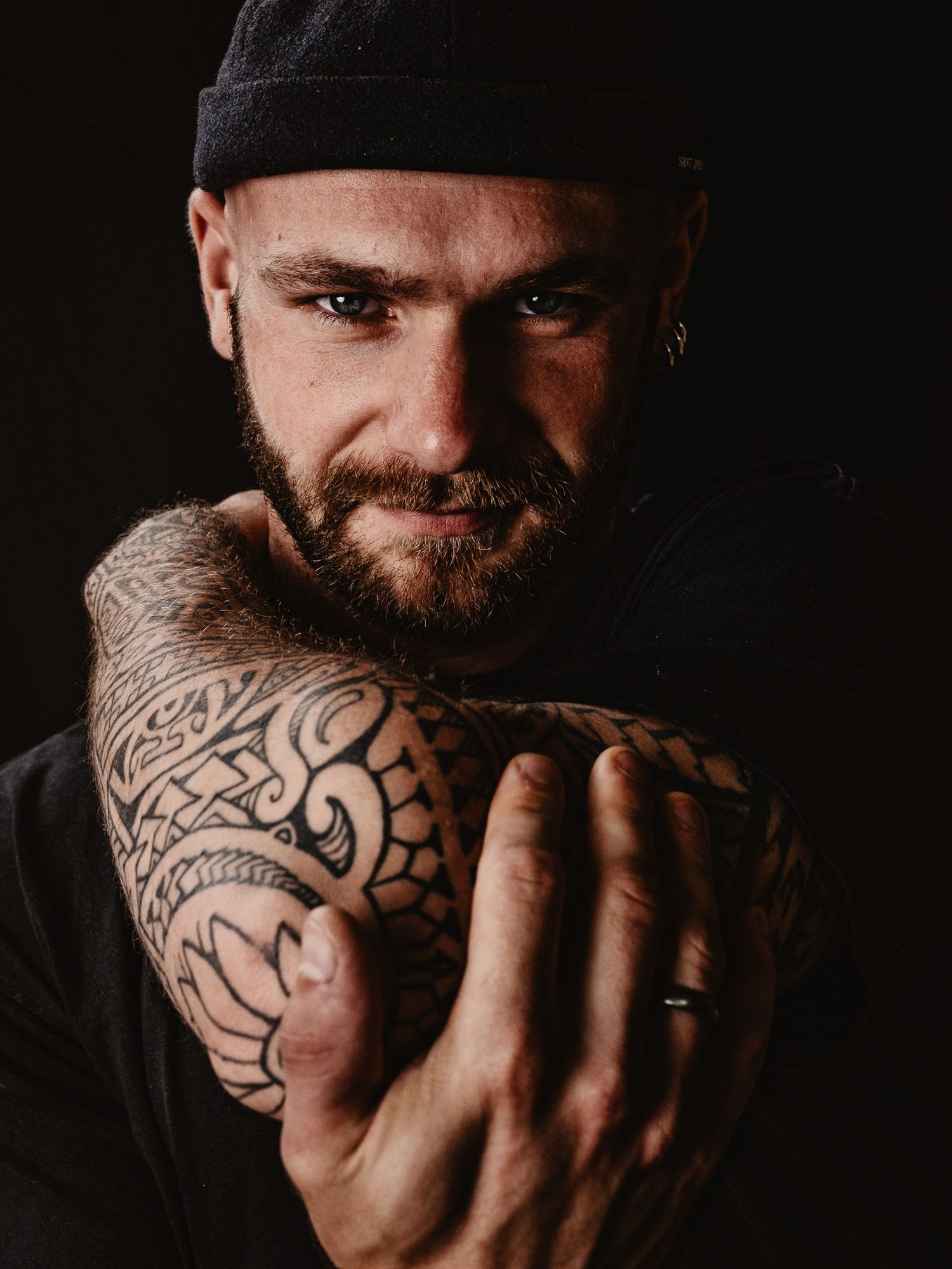 Close-up shots of tattooed arms and face against dark background.
