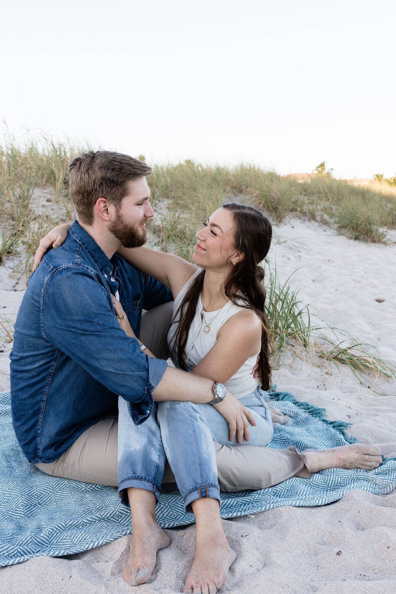 Romantic beach photoshoot with couple sharing tender moments on sand.