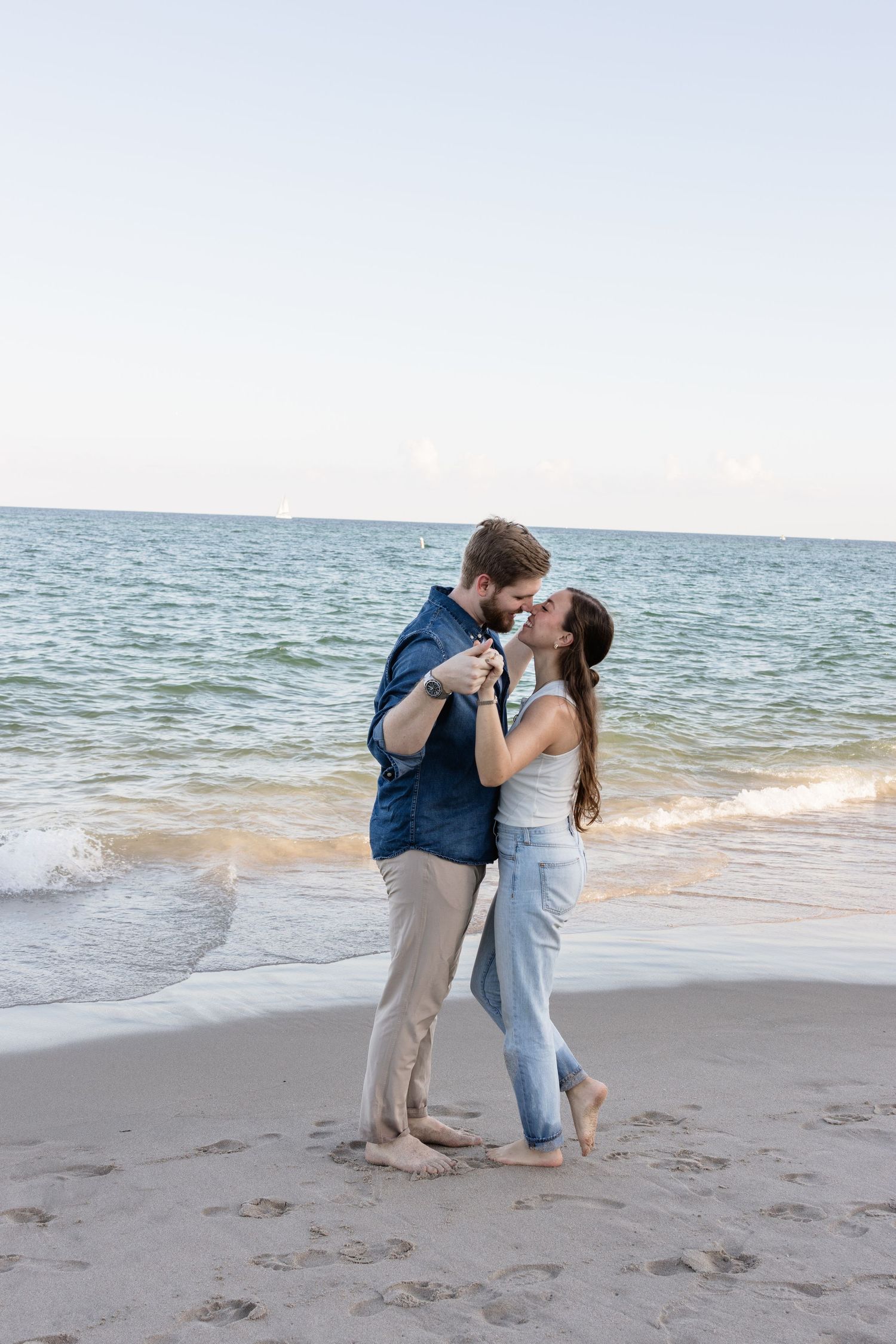 A couple shares a romantic dance and kiss on the beach at sunset.