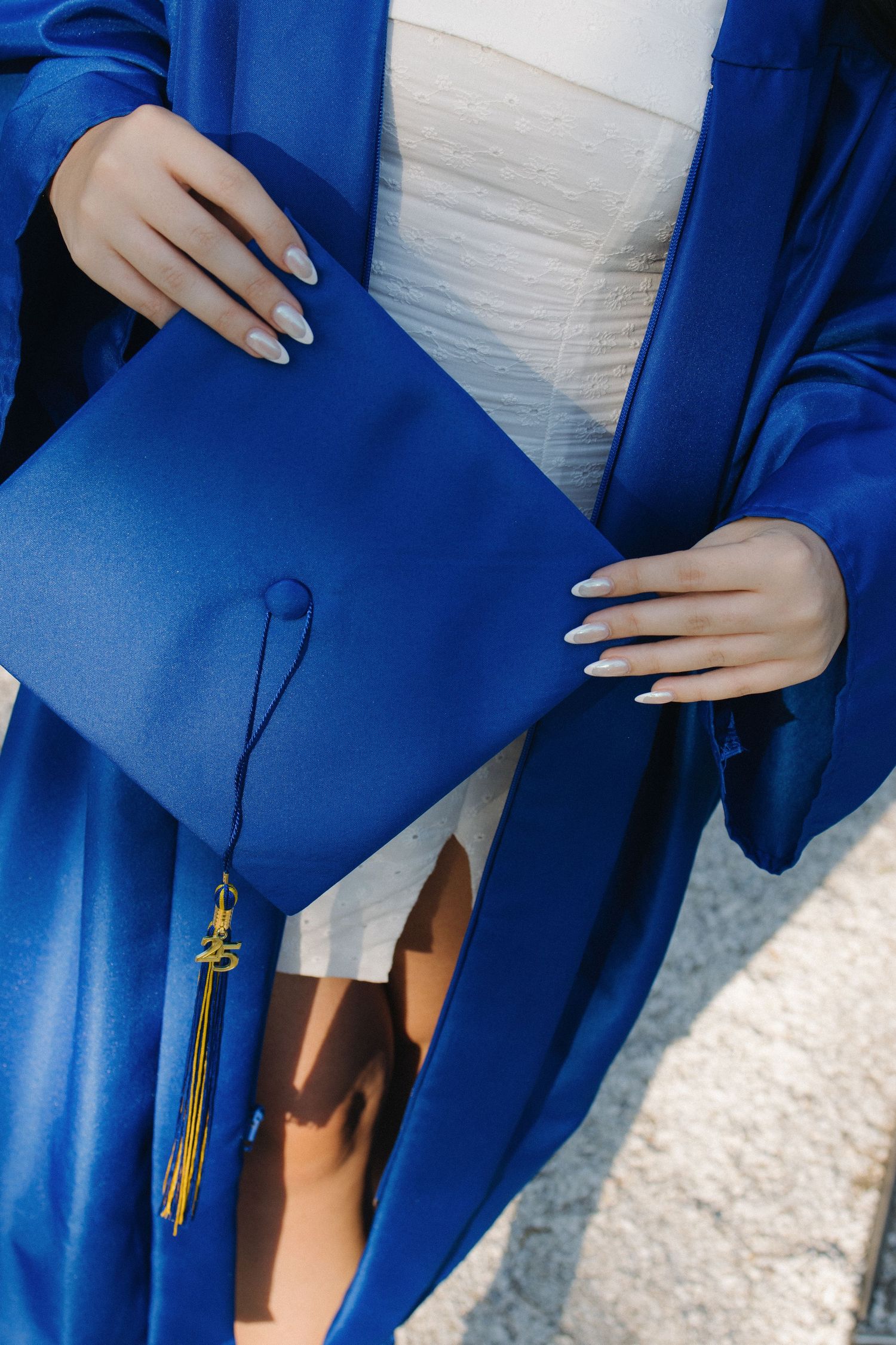 Close-up details of a royal blue graduation gown and tassel.