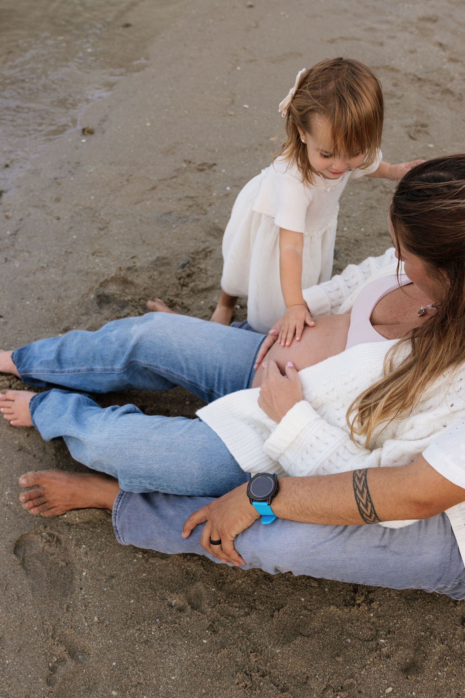 Family relaxing together on the sandy beach at sunset.