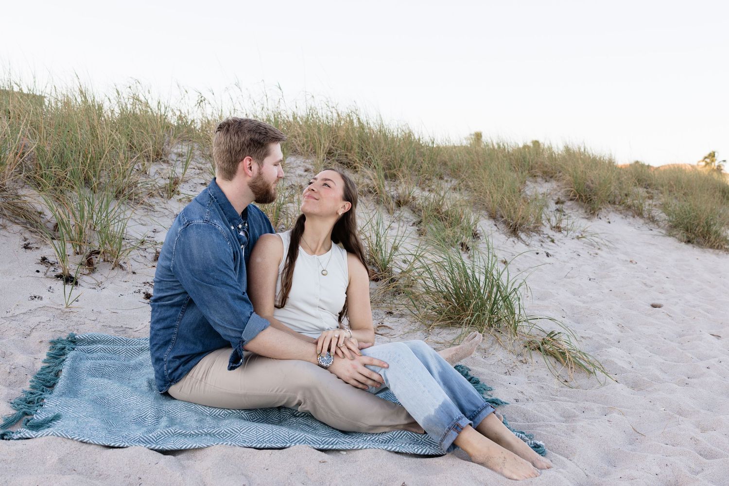 Couple relaxing on a blue blanket in the beach sand dunes.
