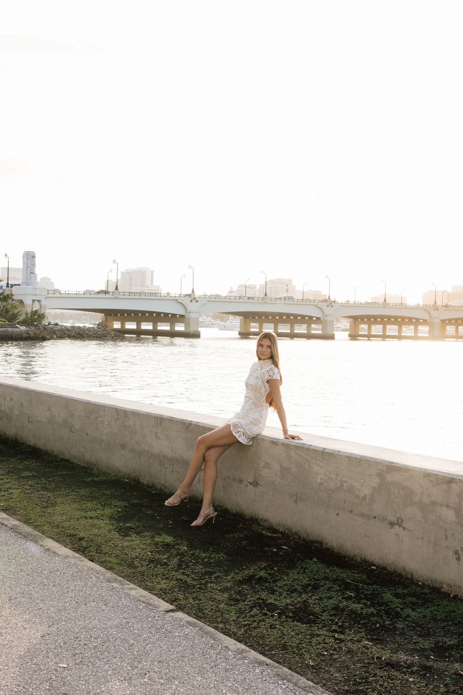 Fashion photography session along waterfront wall at golden hour.